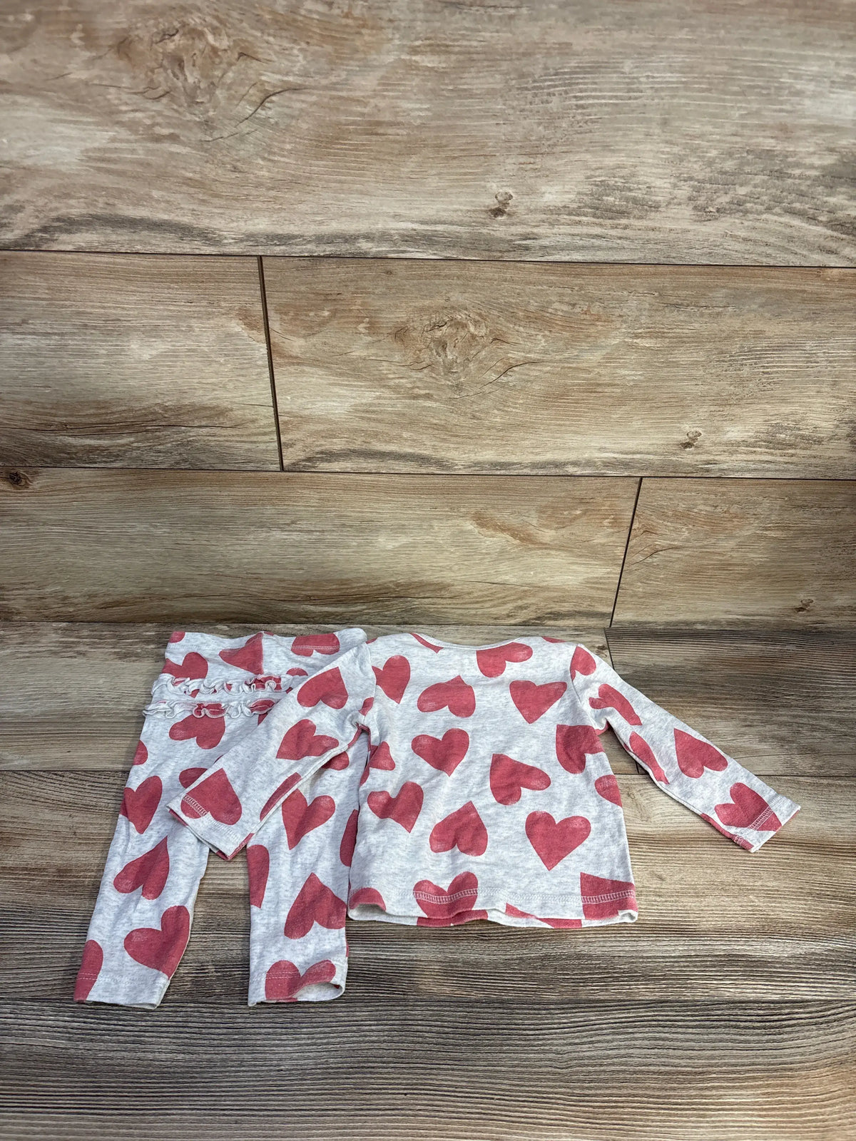 Top-down view of Carter’s two-piece heart print shirt and pants set in gray on a wood floor
