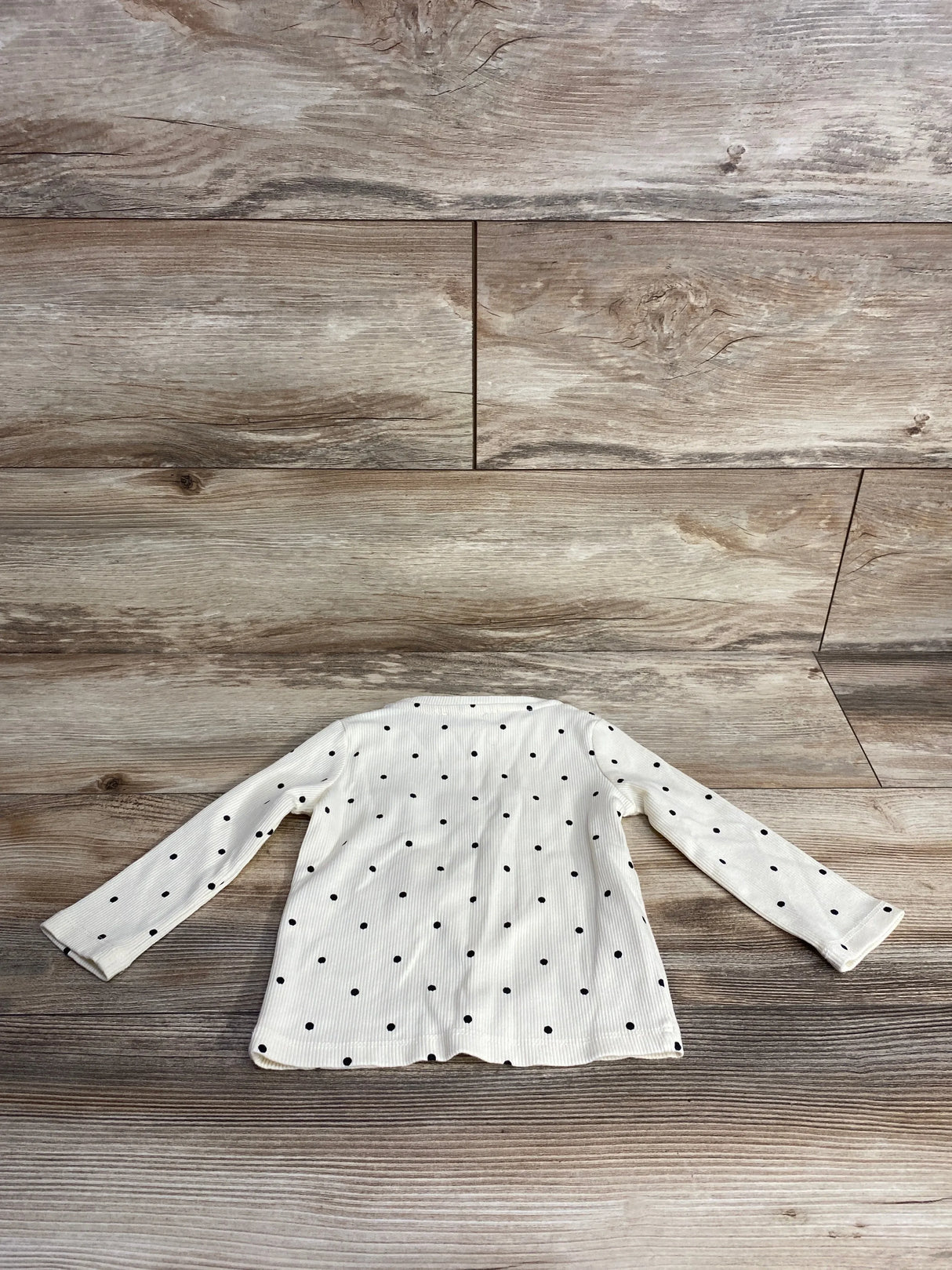 Long sleeve white baby shirt with black polka dots on wooden floor
