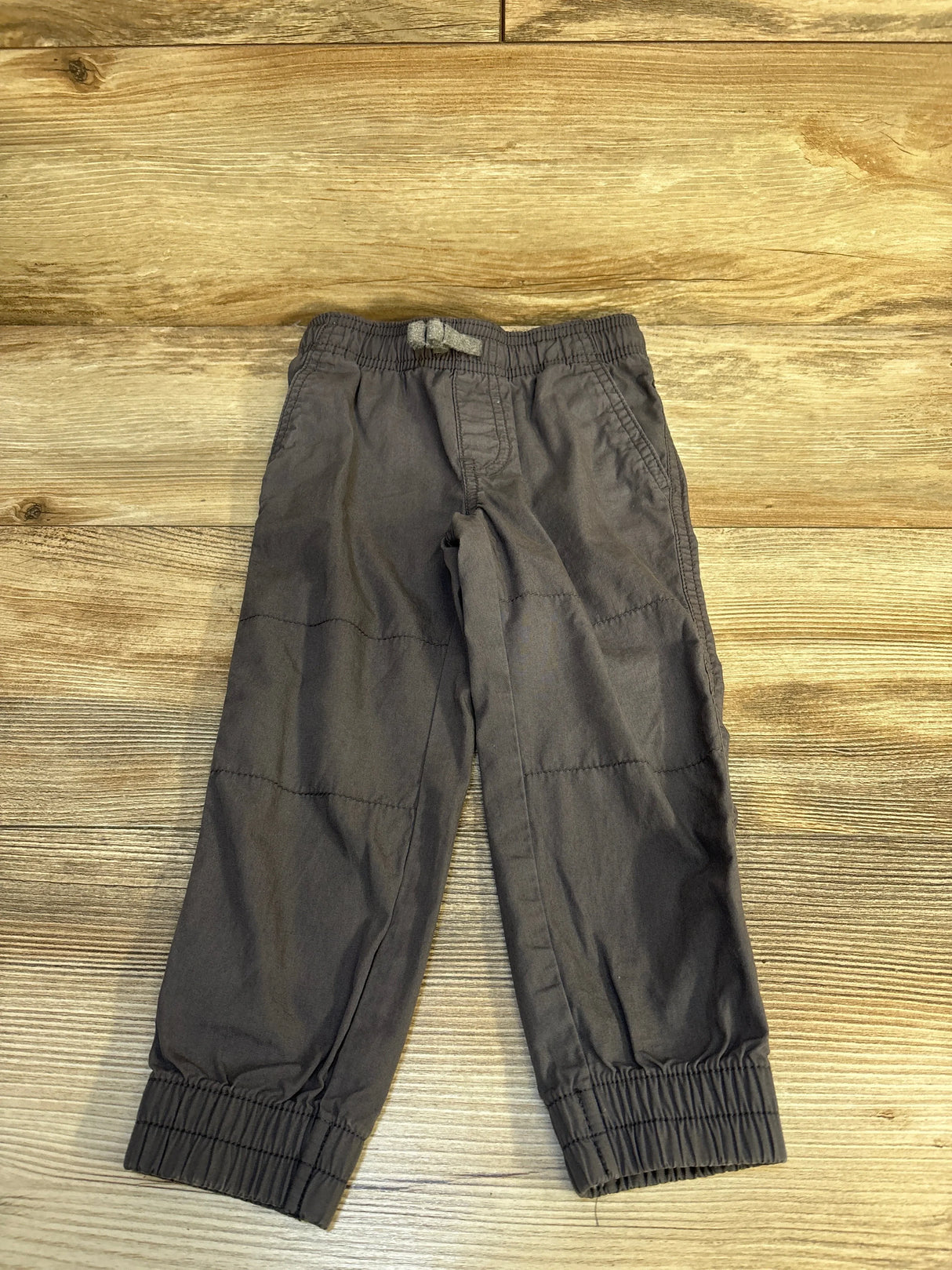Gray toddler cargo pants with elastic waist and cuffs on wood background