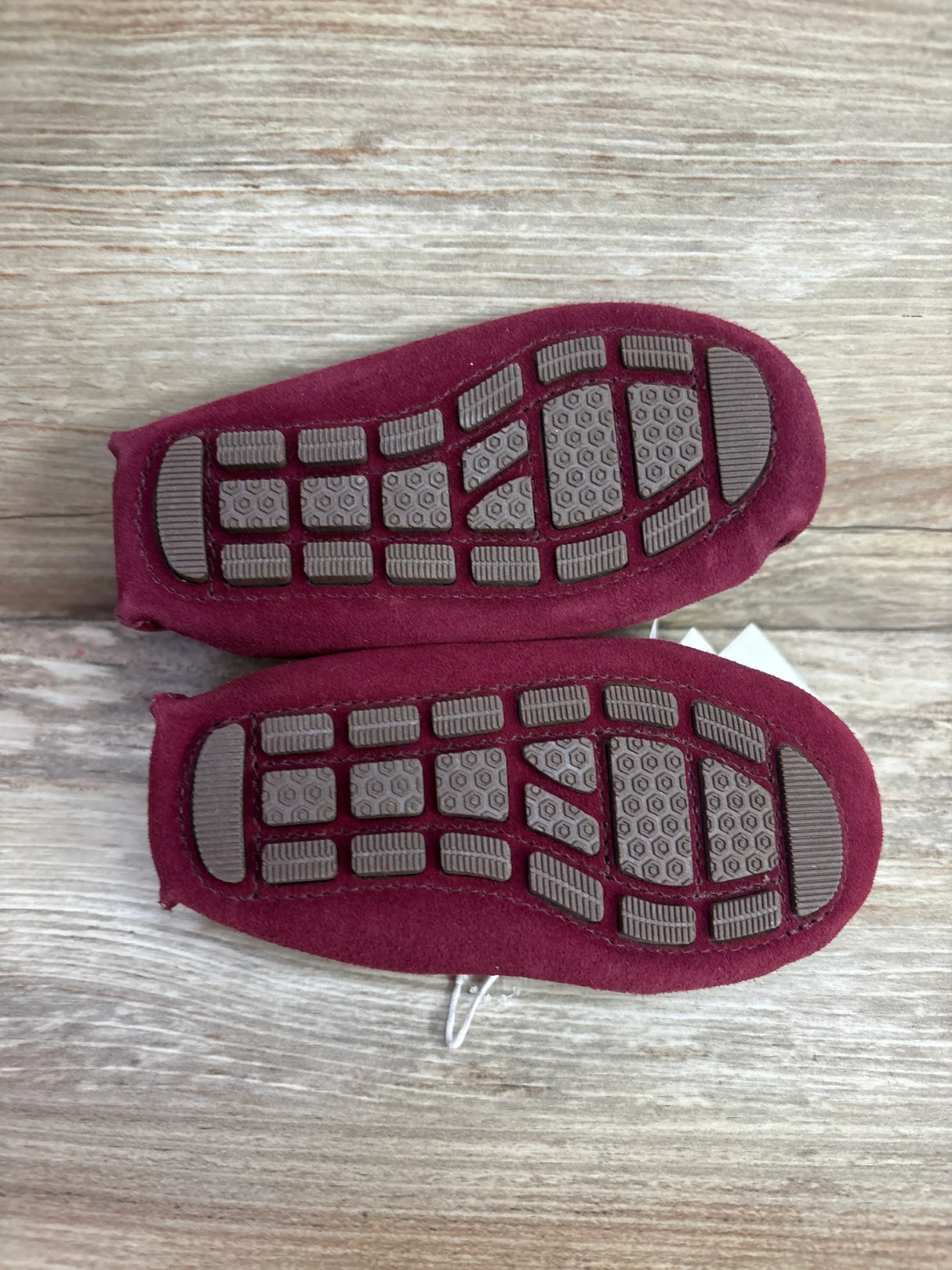 Top-down view of Janie & Jack maroon suede driving shoes size 6C showing brown textured rubber driving soles on wood background