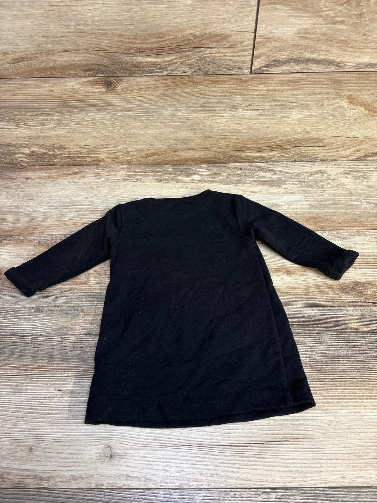 Black long-sleeve toddler dress on wooden floor, ideal for kids' casual wear
