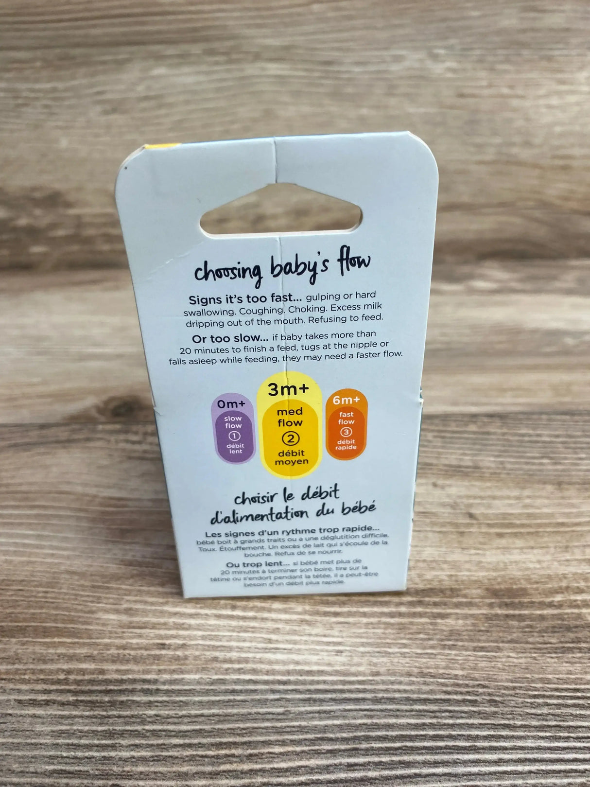 Back view of Tommee Tippee Advanced Anti‑Colic 2‑pack bottle nipples showing “choosing baby’s flow” guide and 0m/3m/6m flow icons on wood