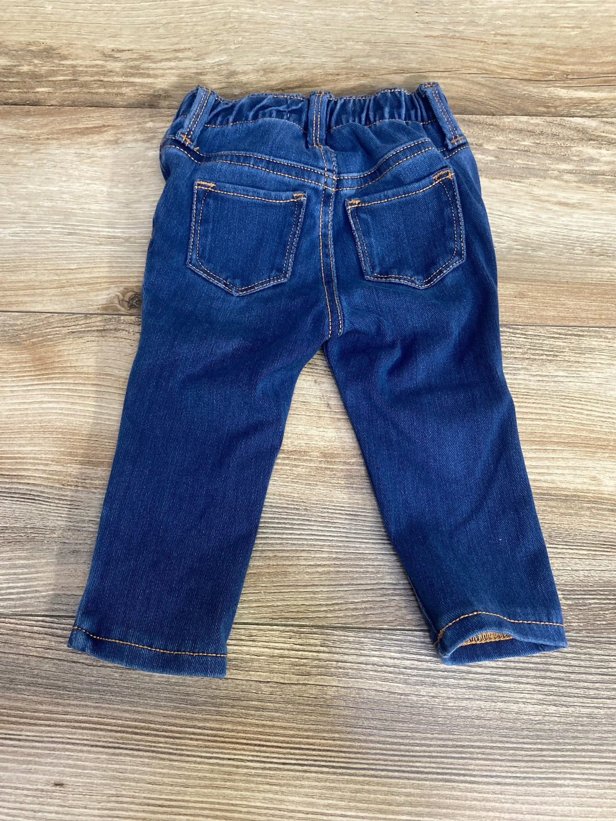Back view of Old Navy Rockstar jeggings in blue size 12-18 months showing elastic waistband and two back patch pockets on a wooden floor