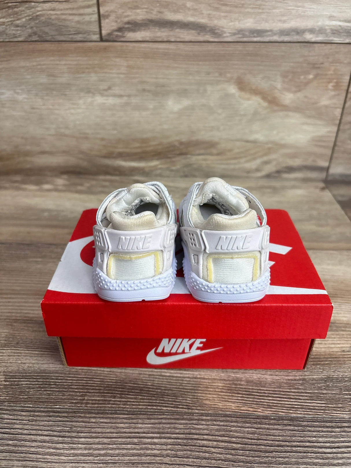Rear view of Nike Air Huarache Run TD toddler sneakers showing molded heel strap and cushioned collar on red Nike box on wood floor