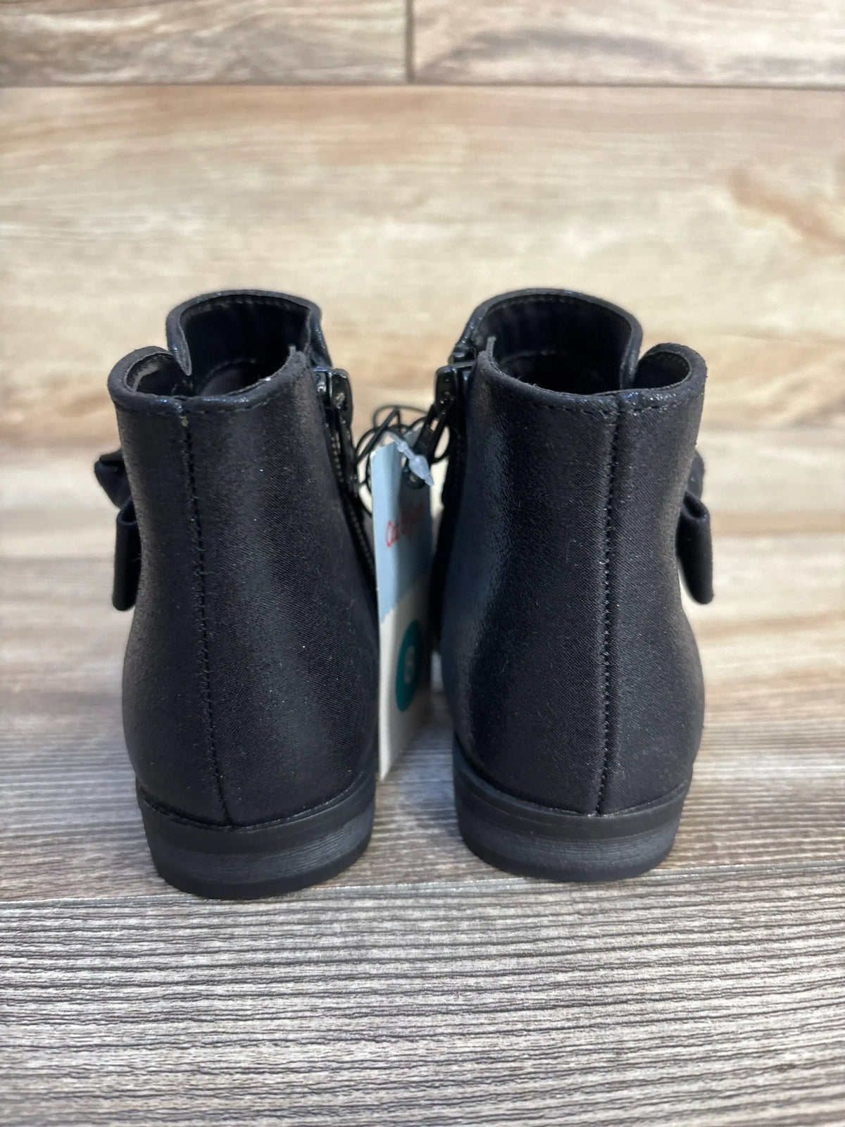 Back view of black toddler ankle boots on wood floor with tags attached