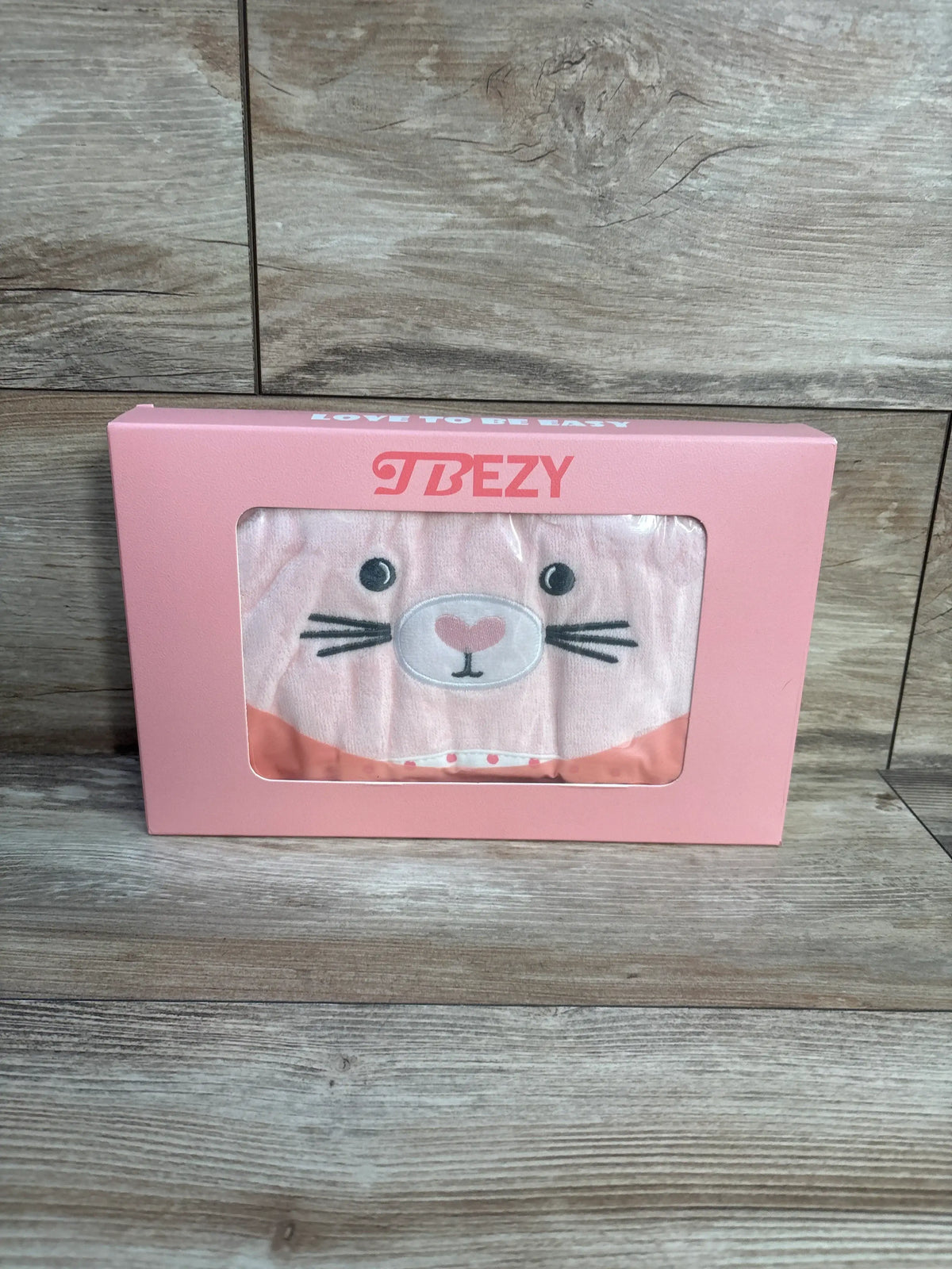 Front view of pink TBEZY hooded bunny towel in a pink box, showcasing the bunny face design on a wood grain surface