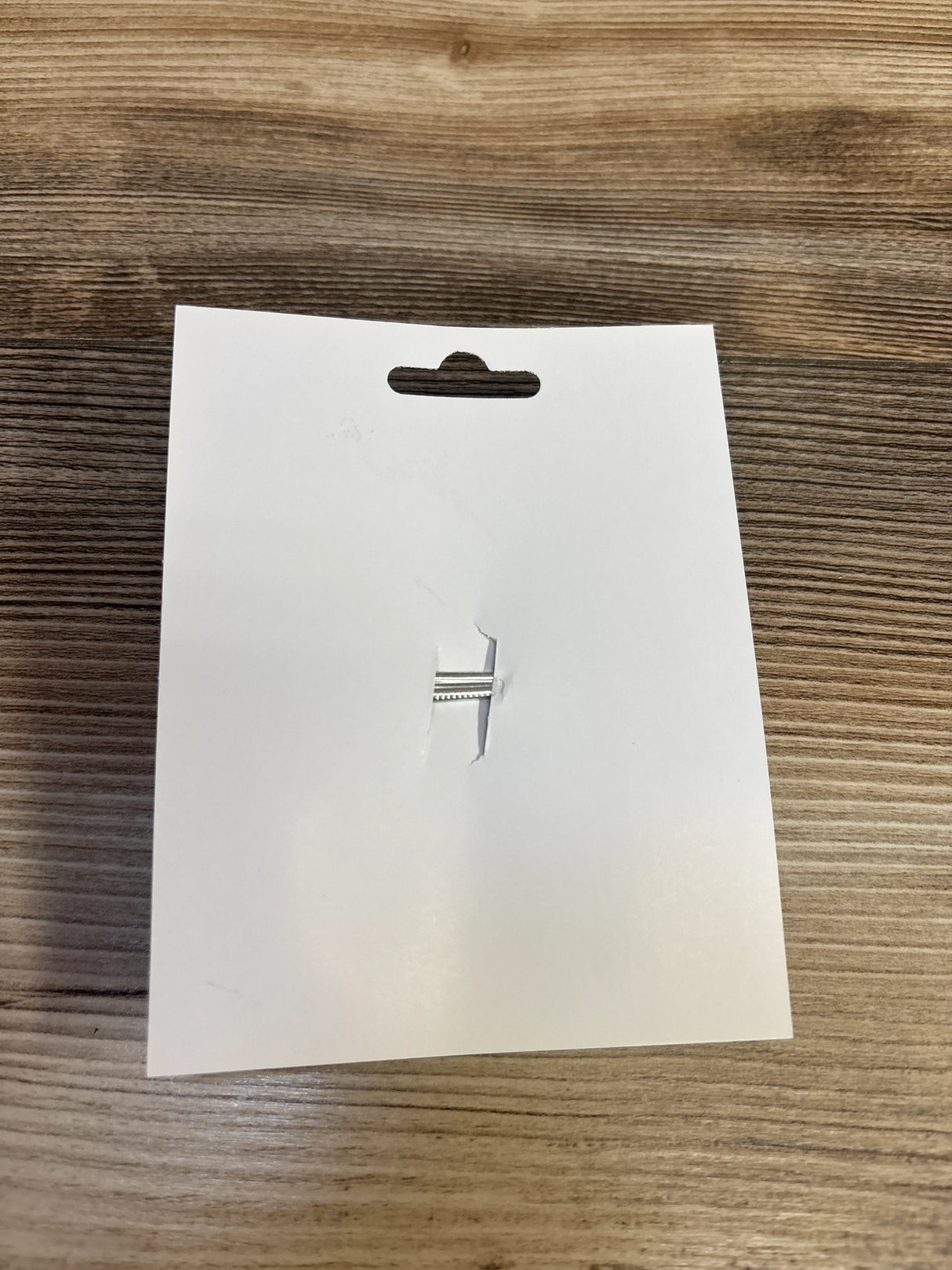 White packaging card with hanging tab slot on wood surface