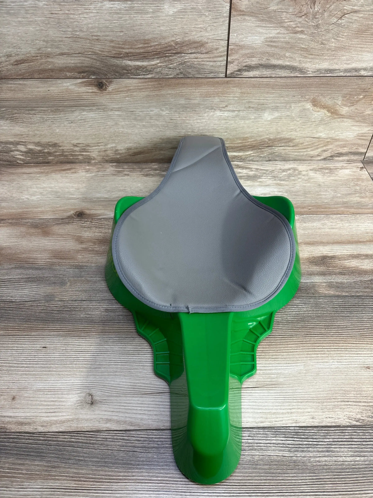 Top view of Crawligator tummy time toy in green showing gray padded seat and raised backrest on wood floor