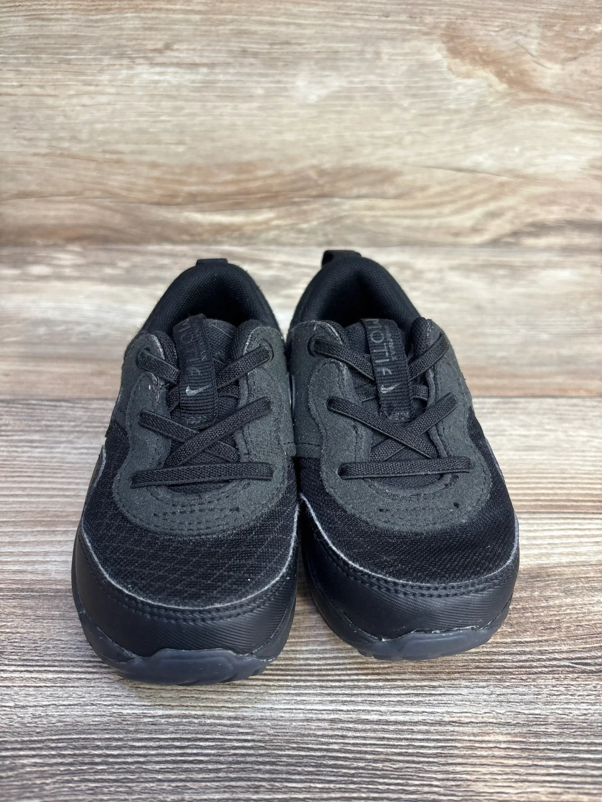Front view of Nike Air Max Motif toddler sneakers (sz 8C) showcasing black mesh and suede upper, laces, and Air Max sole on wood floor