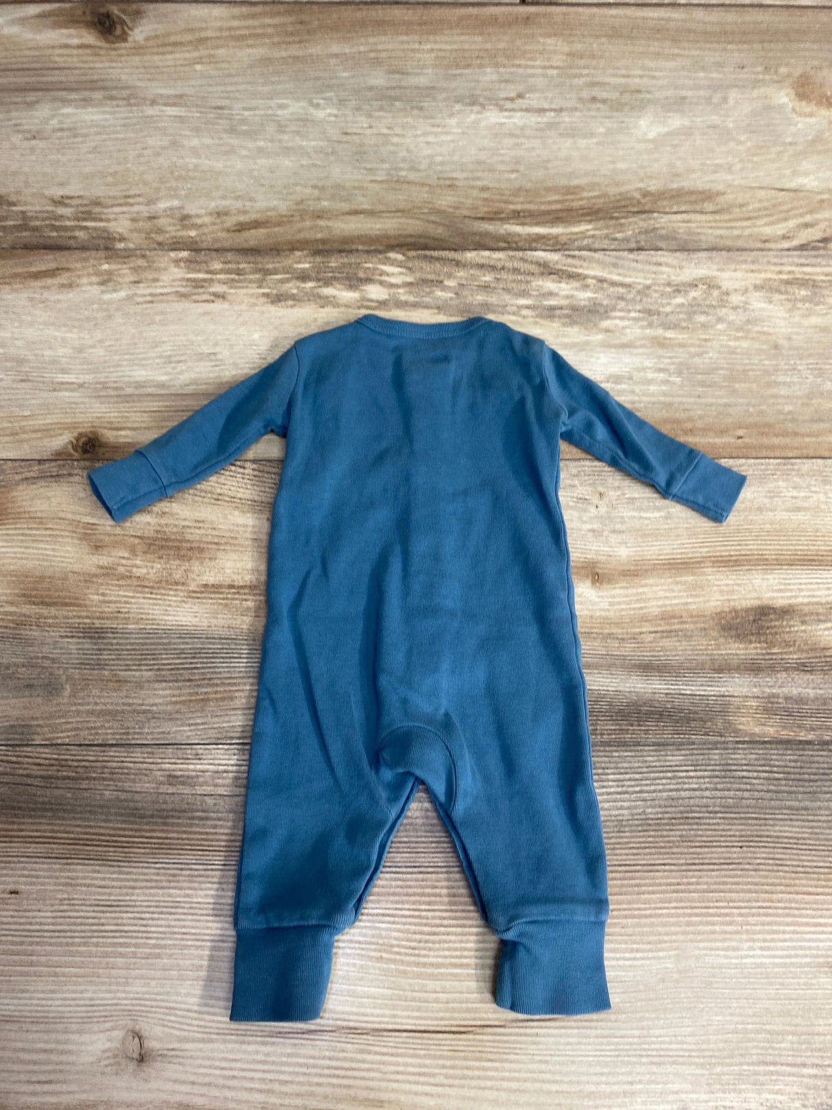 Blue long sleeve baby romper laid flat on wood background