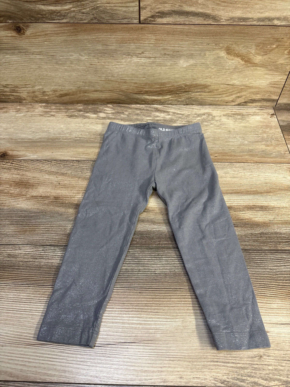 Front view of Old Navy glitter leggings in grey, size 2T showcasing the glitter finish on a wood background