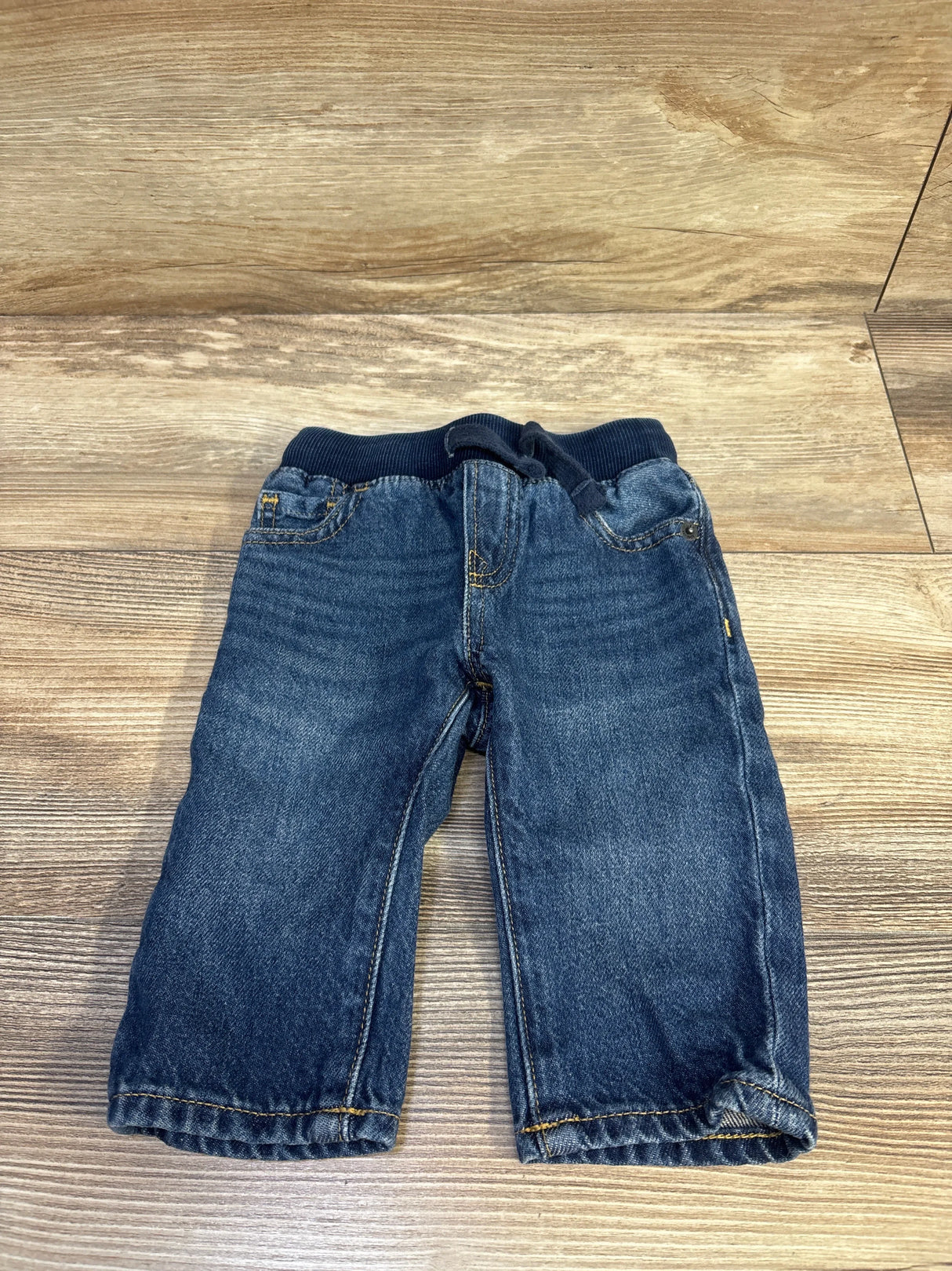 Front view of Baby Gap pull-on straight baby jeans in blue showing ribbed elastic waistband with drawstring and faded wash on wood floor