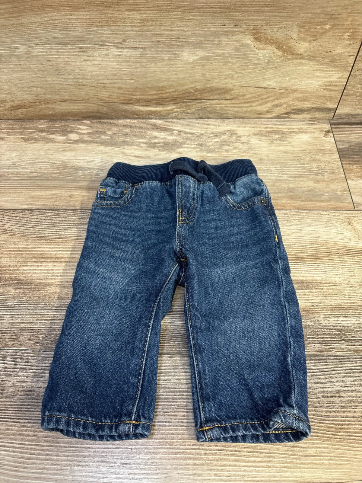 Front view of Baby Gap pull-on straight baby jeans in blue showing ribbed elastic waistband with drawstring and faded wash on wood floor