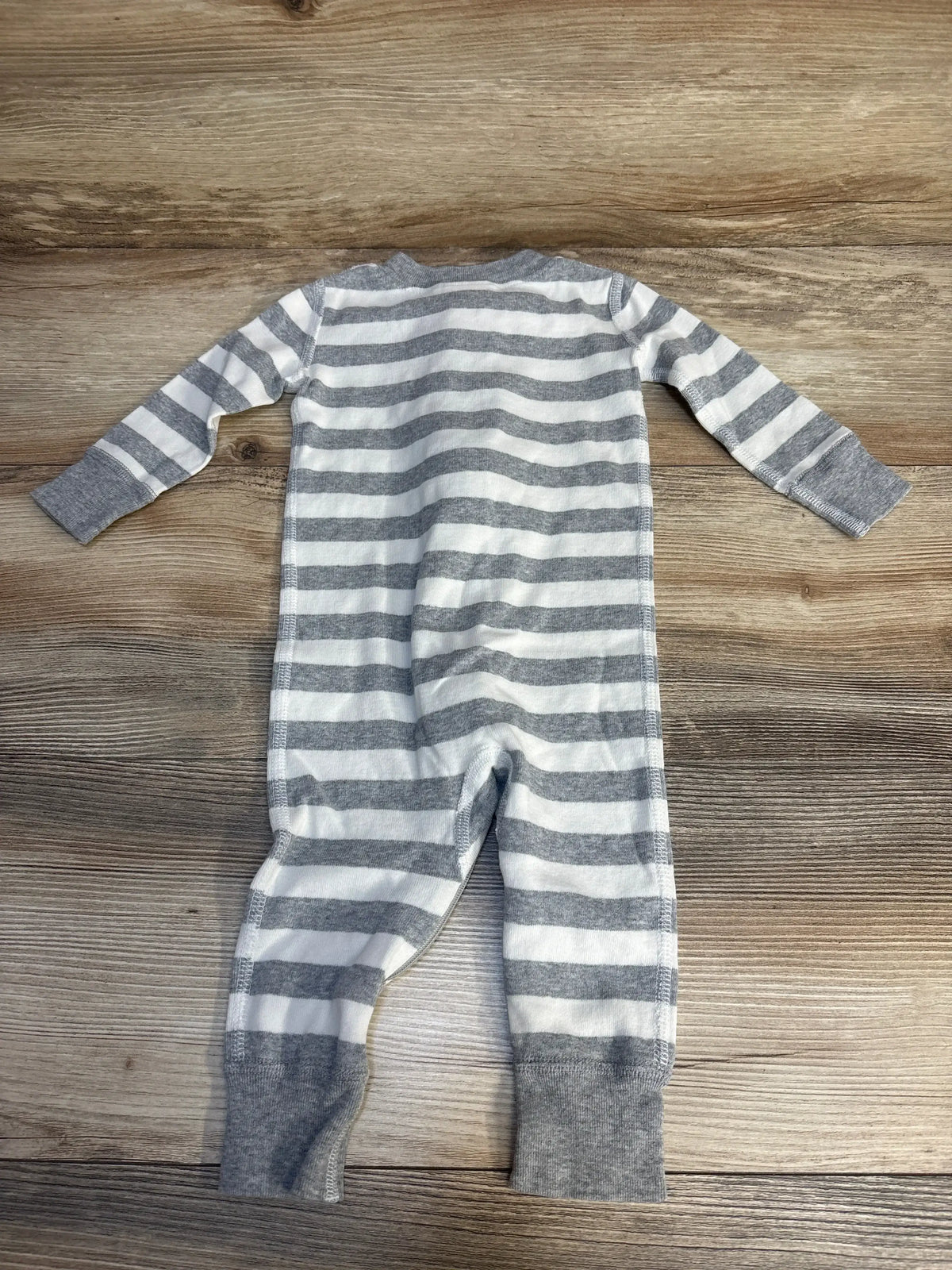 Gray and white striped baby sleeper with long sleeves on wooden background