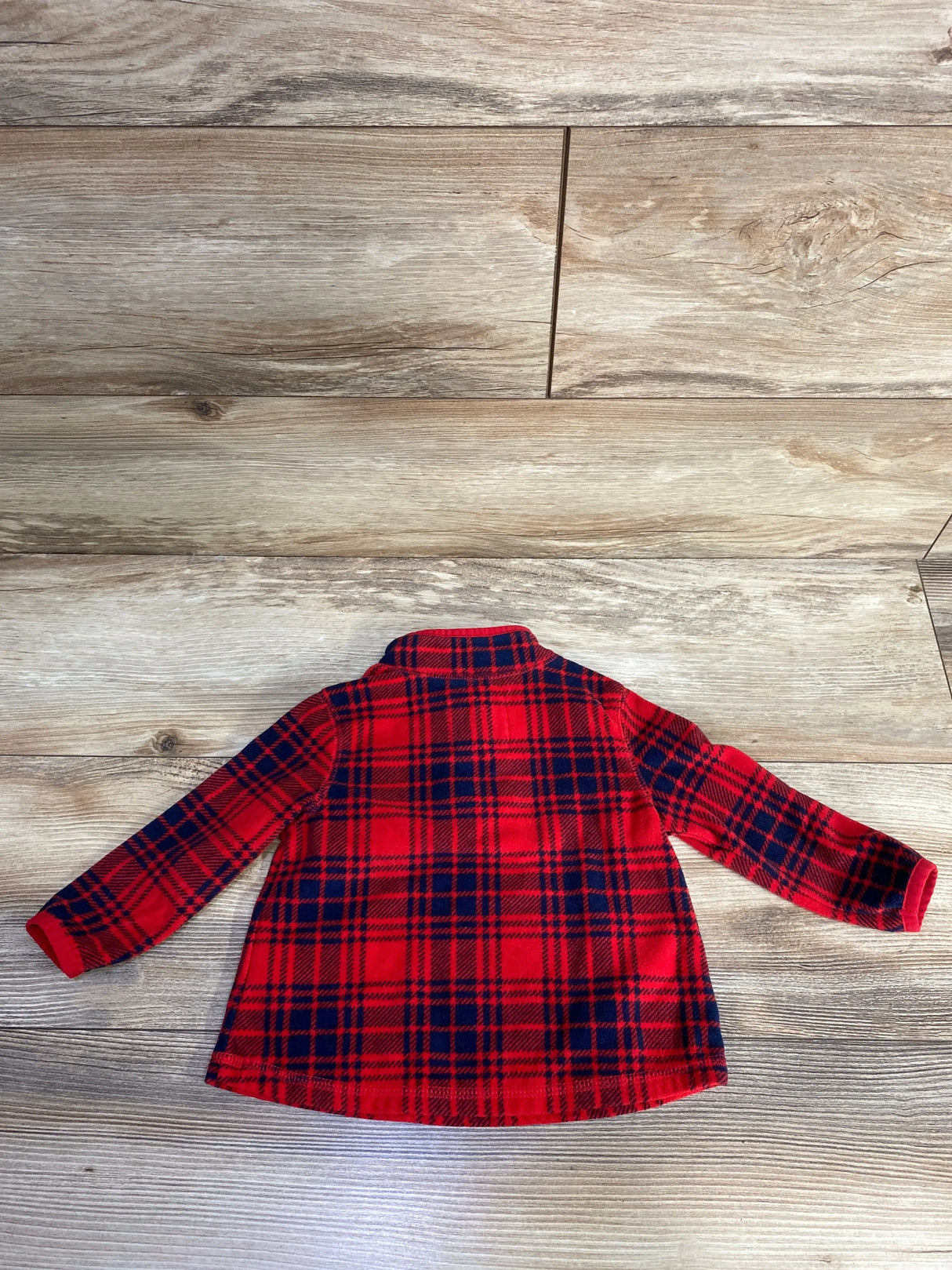 Red and black plaid long sleeve shirt for kids on wood floor
