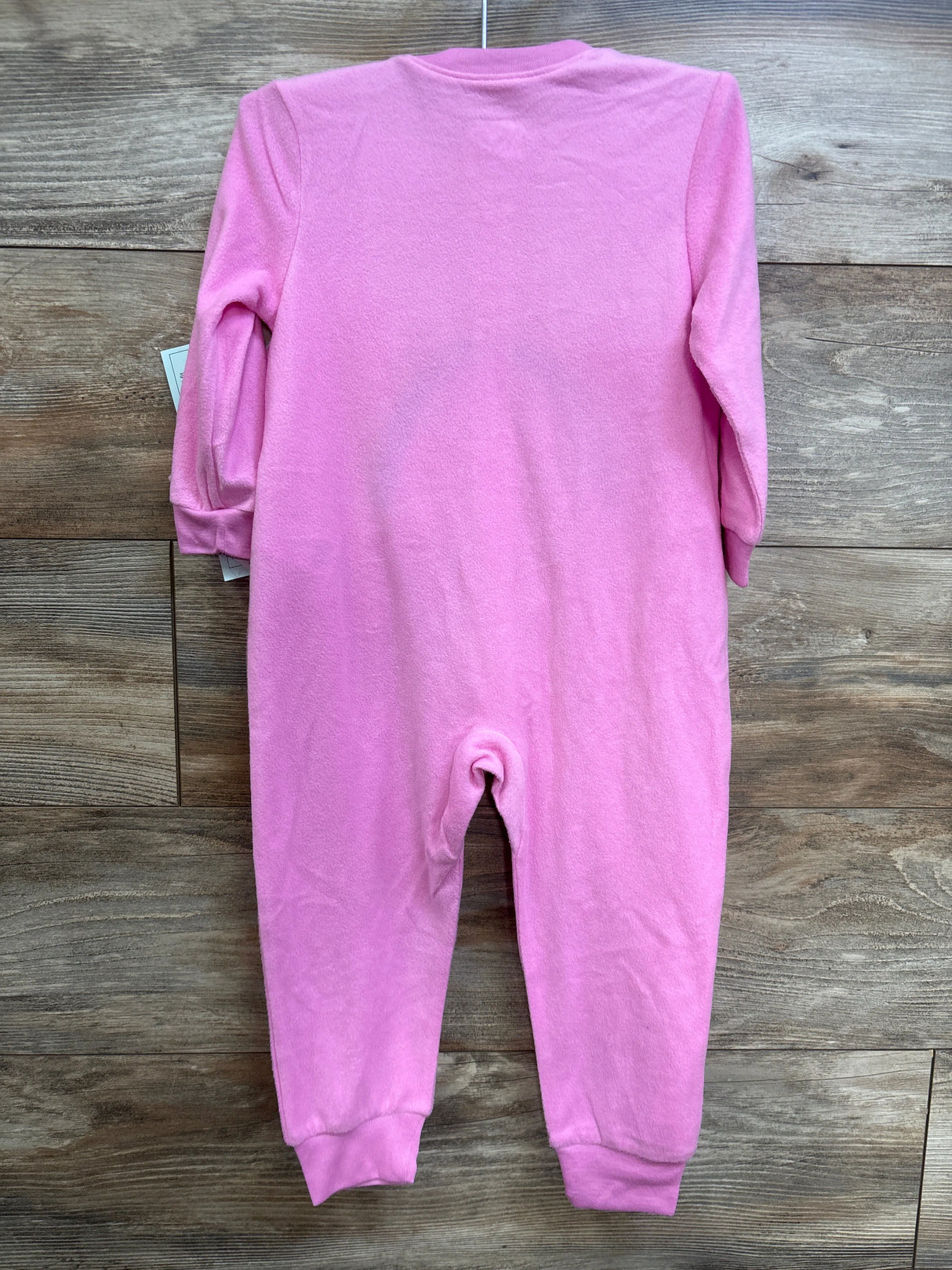 Back view of pink Care Bears toddler sleeper showing long sleeves and cuffed ankles against wood plank background