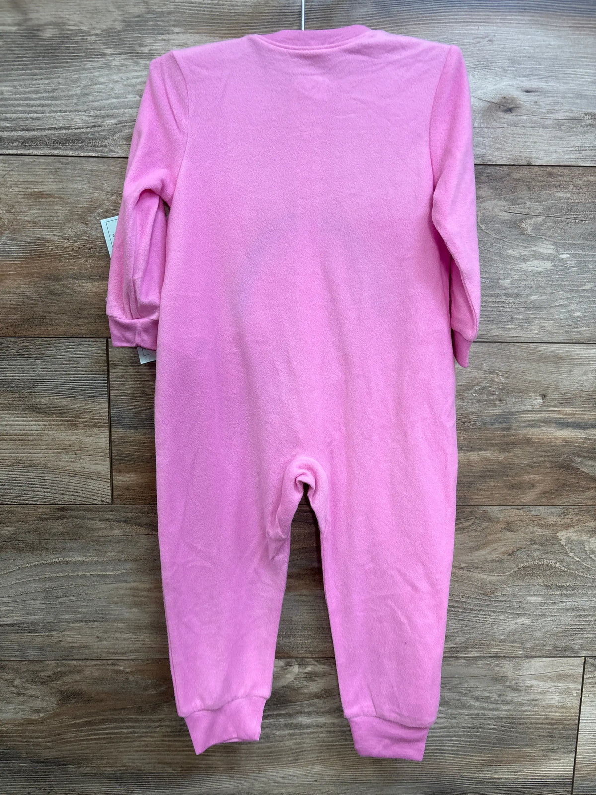 Back view of pink Care Bears toddler sleeper showing long sleeves and cuffed ankles against wood plank background