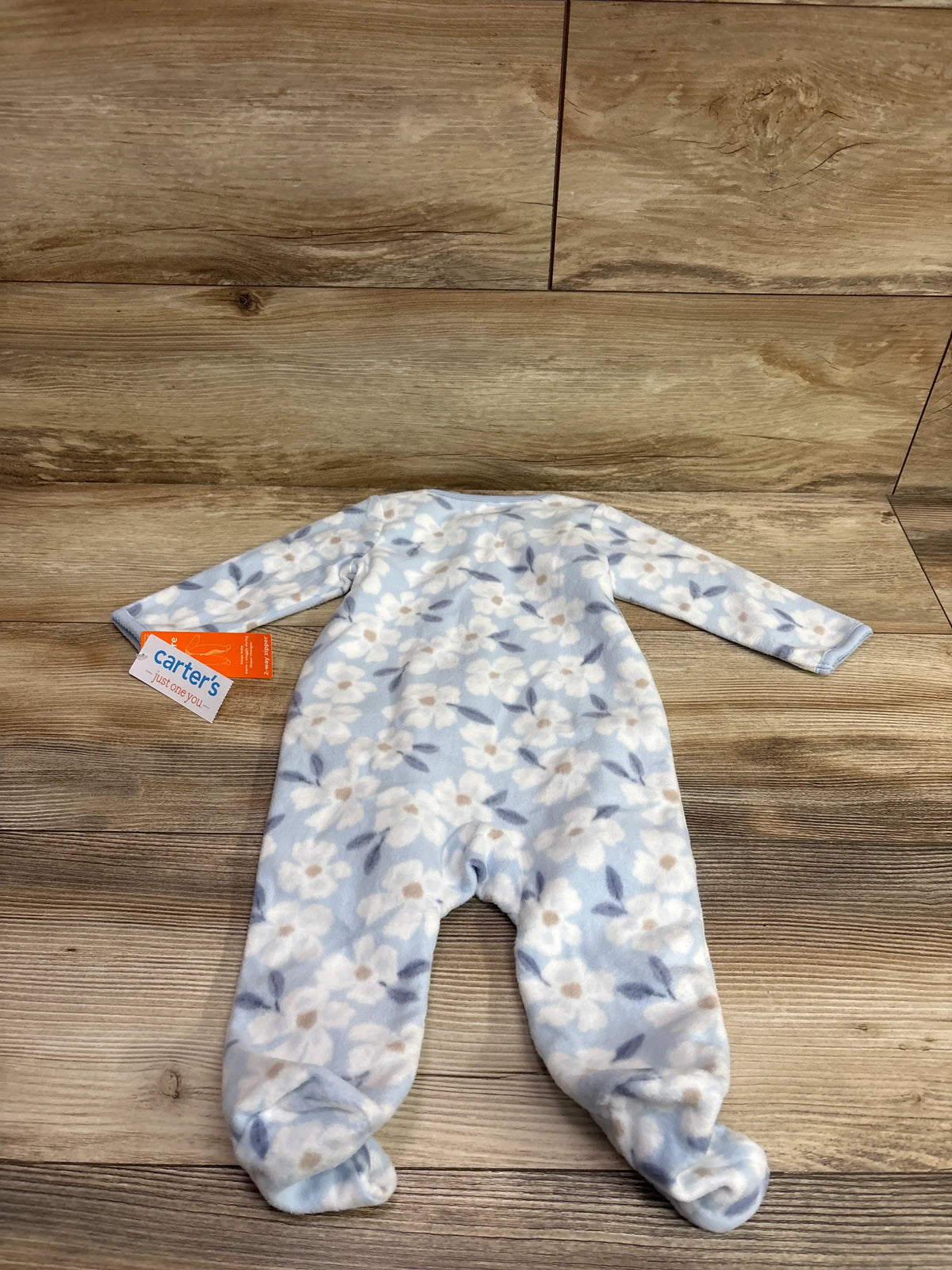 Front view of a blue floral Just One You blanket sleeper showcasing long sleeves and footed legs on a wood floor