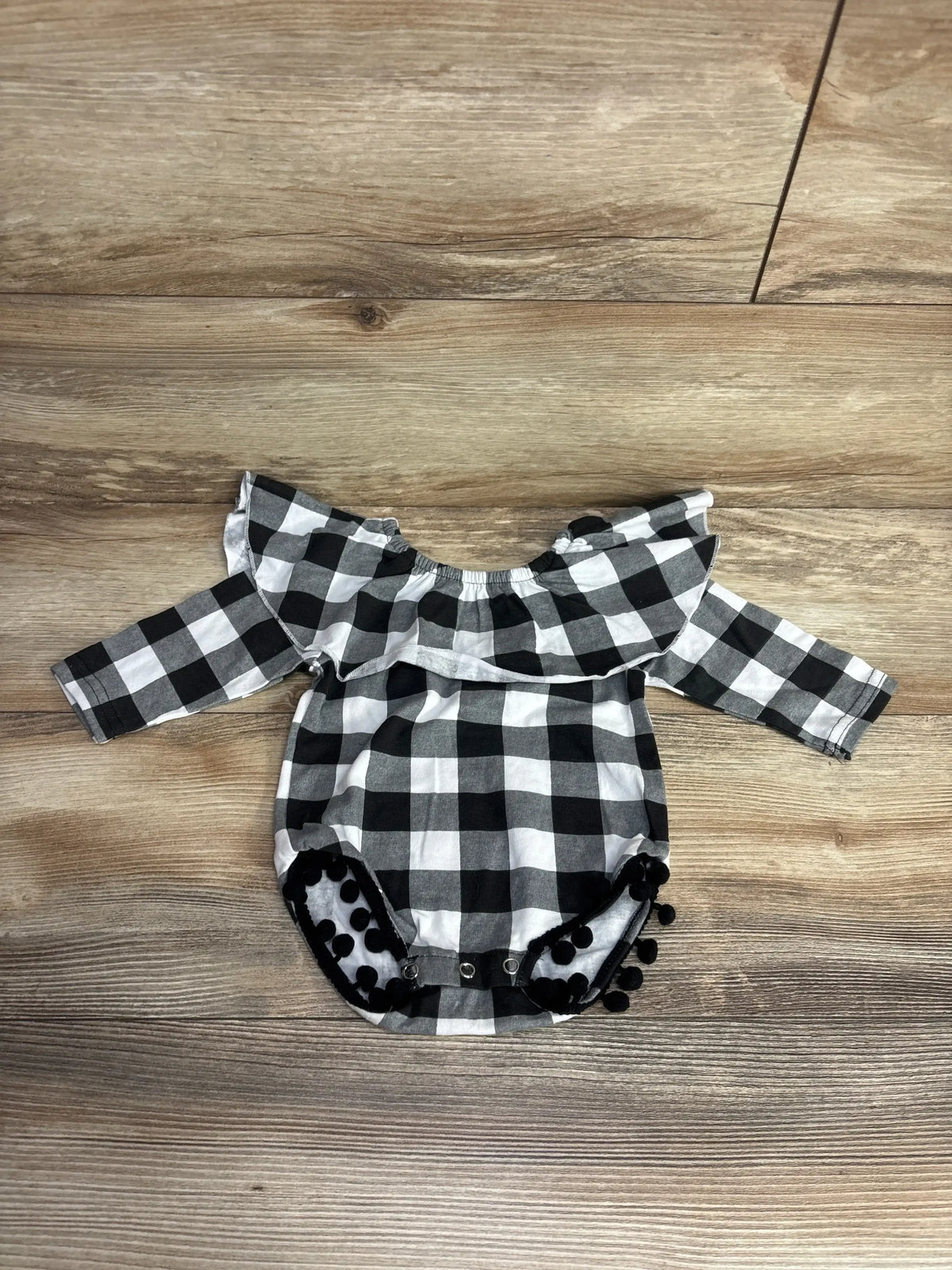 Black and white checkered long-sleeve baby romper with ruffle detail and snap buttons