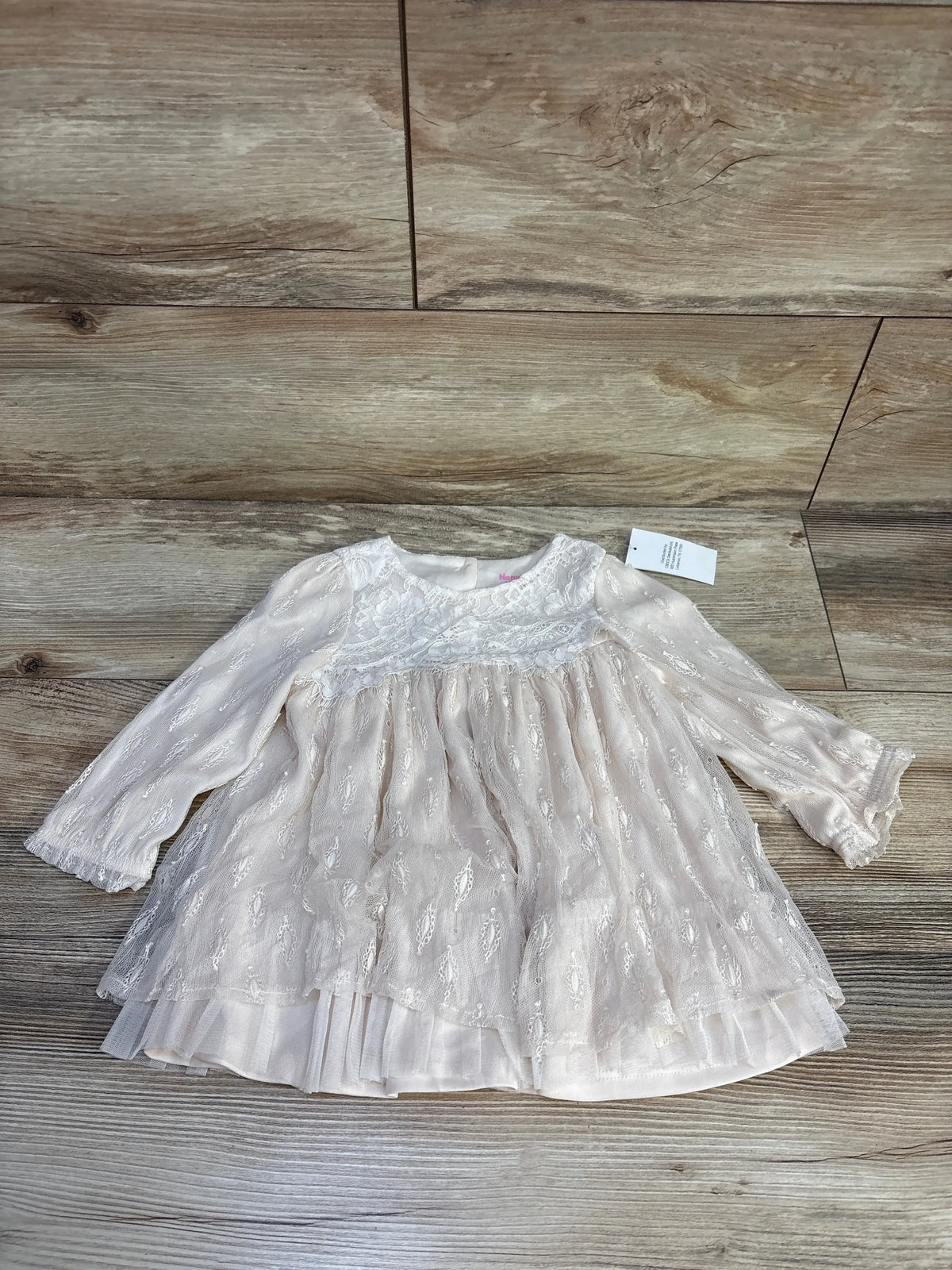 Front view of Nannette Baby cream lace top showcasing long sleeves, lace overlay, and layered ruffle hem on a wood-look floor