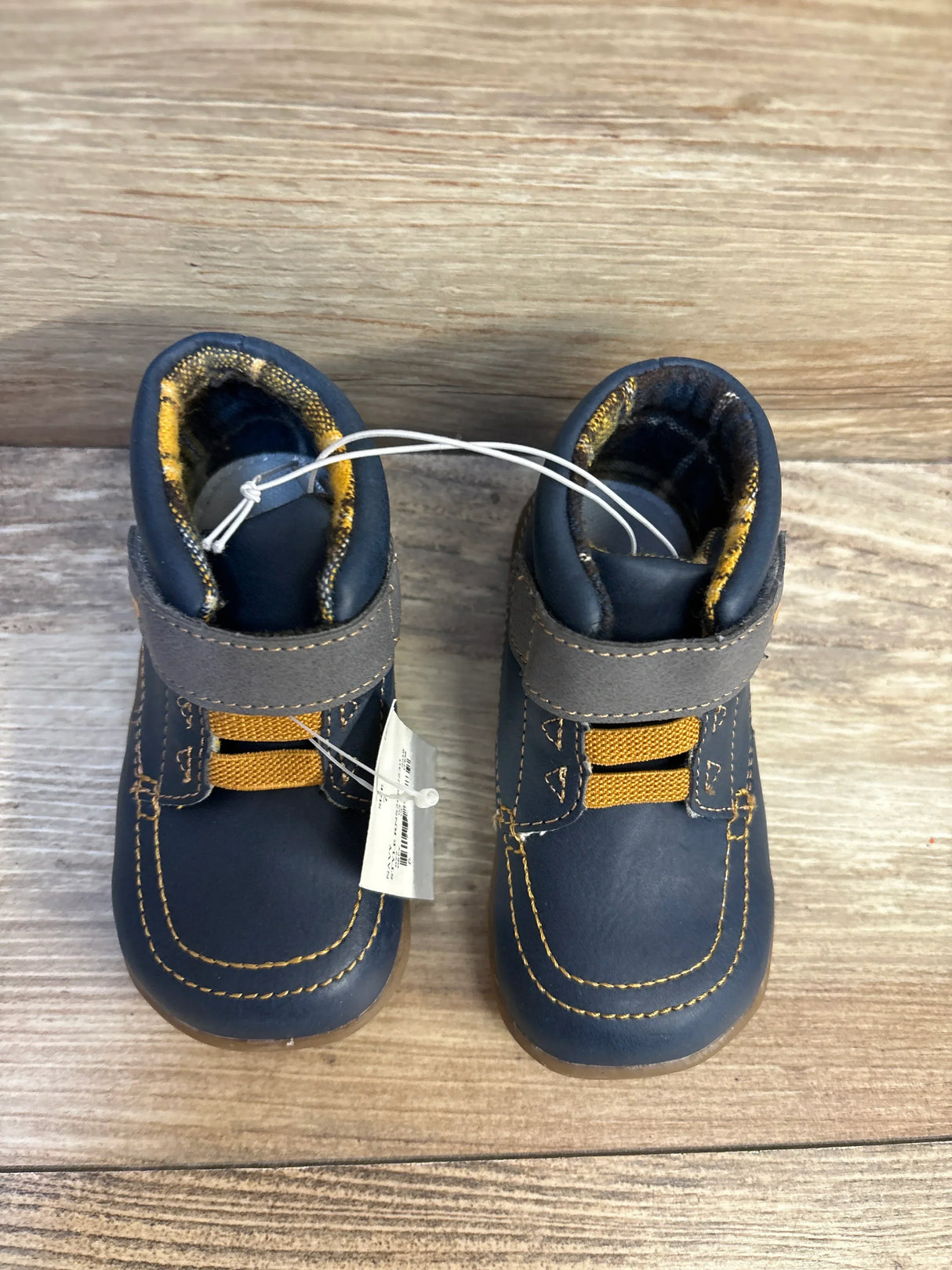 Navy blue toddler shoes with gray straps and yellow accents on wooden floor