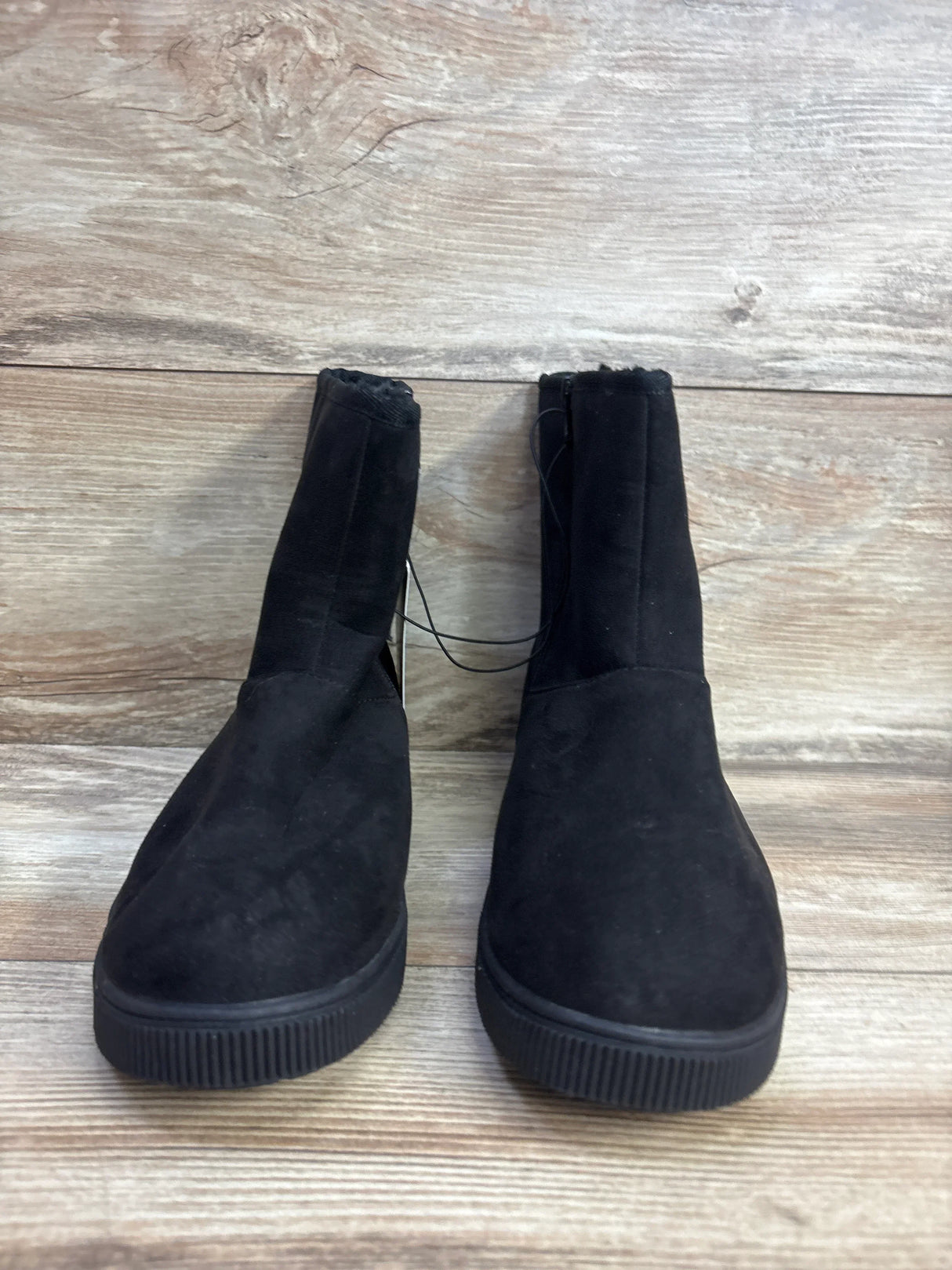 Pair of black suede slip-on boots for kids on wooden background