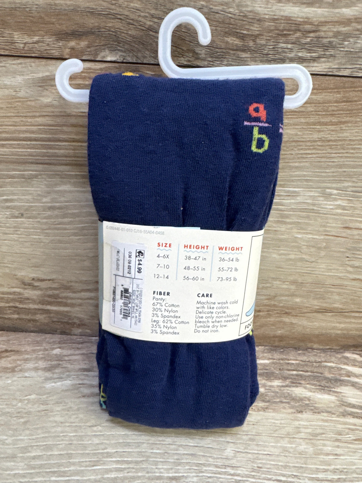 Front view of folded Cat & Jack navy cotton tights size 12-14 showing size chart label and hanger on wood background