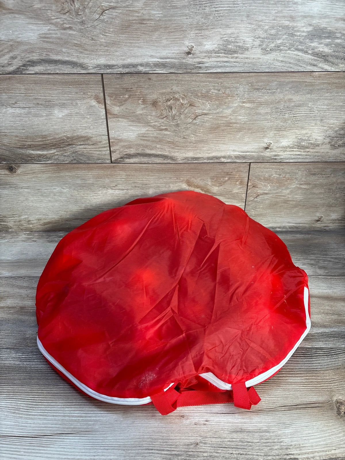 Top view of Bestway multicolor plastic ball pit balls storage bag showcasing red fabric and white trim on wood flooring