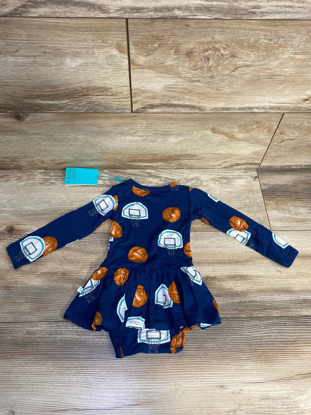 Flat lay of Posh P Swish twirl skirt bodysuit dress, navy, showing attached bodysuit and basketball print on wooden floor