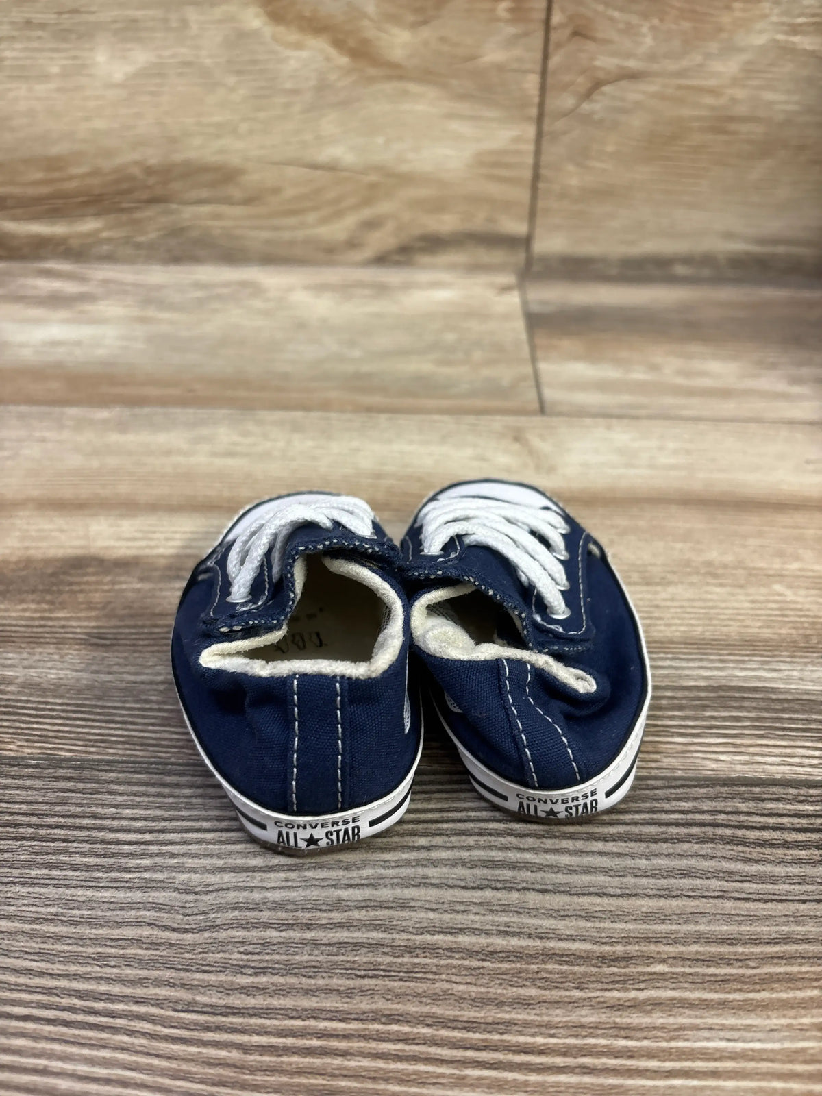 Rear view of navy Converse All Star Cribster Easy-On Shoes showcasing white laces and branded rubber soles on a wood-grain floor