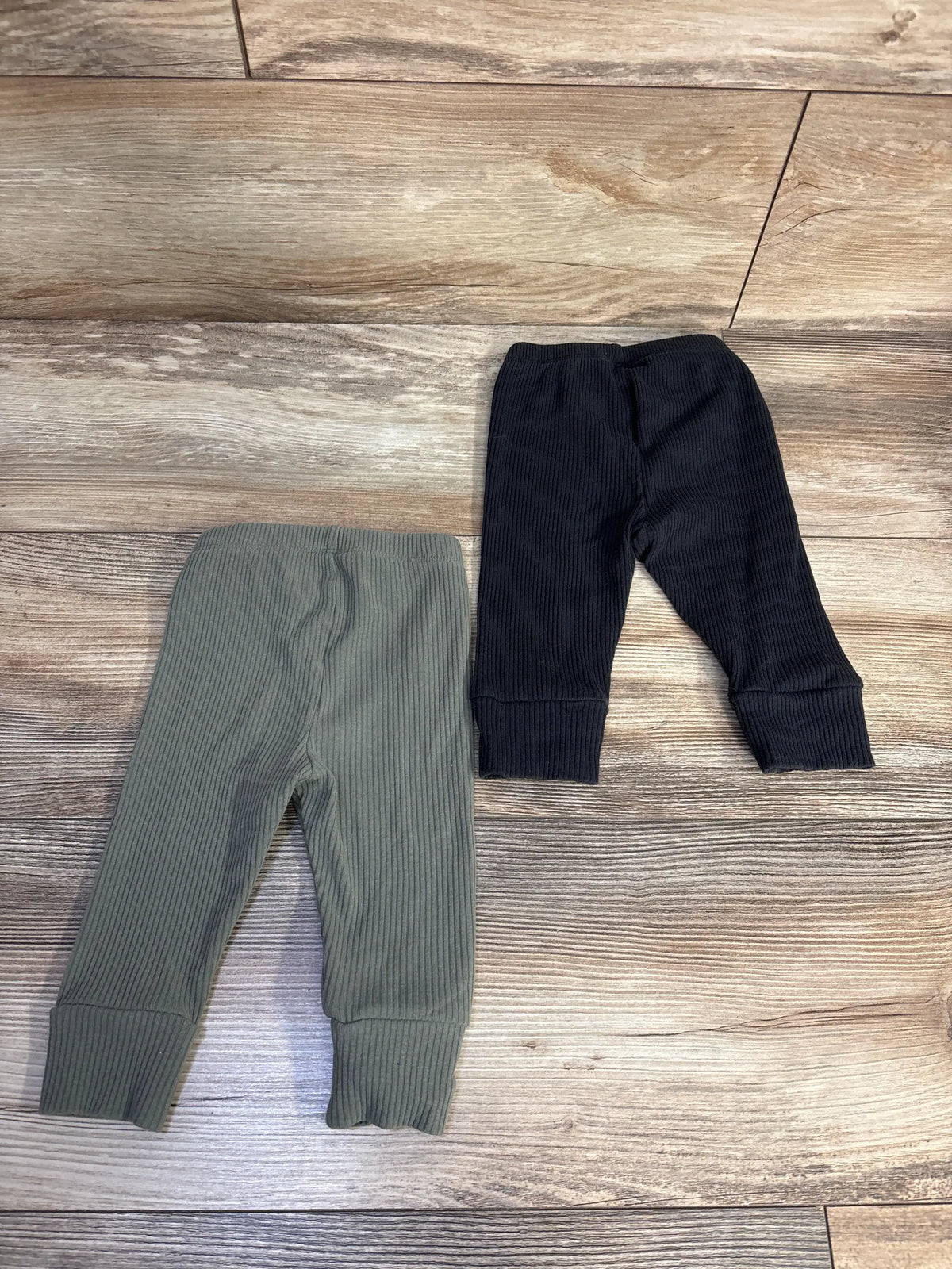Top-down view of Baby Gap 2pk ribbed pull-on pants in black, showcasing ribbed fabric, elastic waists, and cuffed hems
