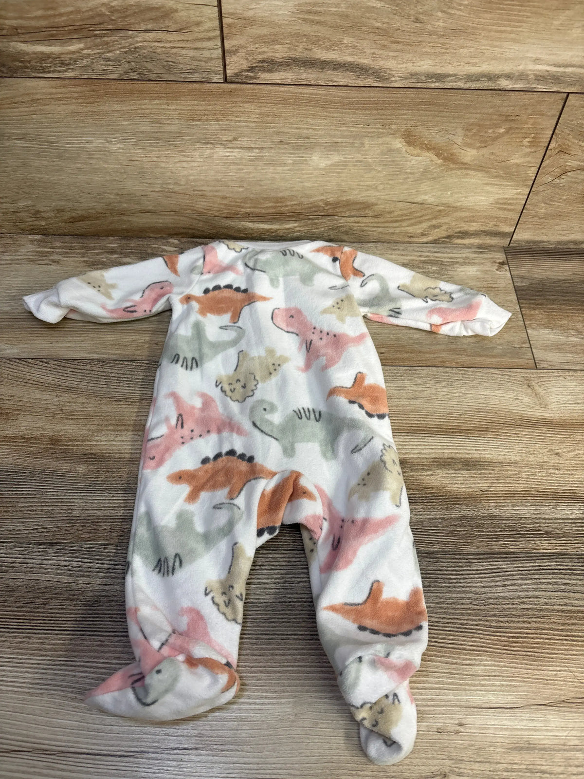 Front view of Carter’s white dinosaur blanket sleeper in size 3 months showcasing footed legs on a wood floor