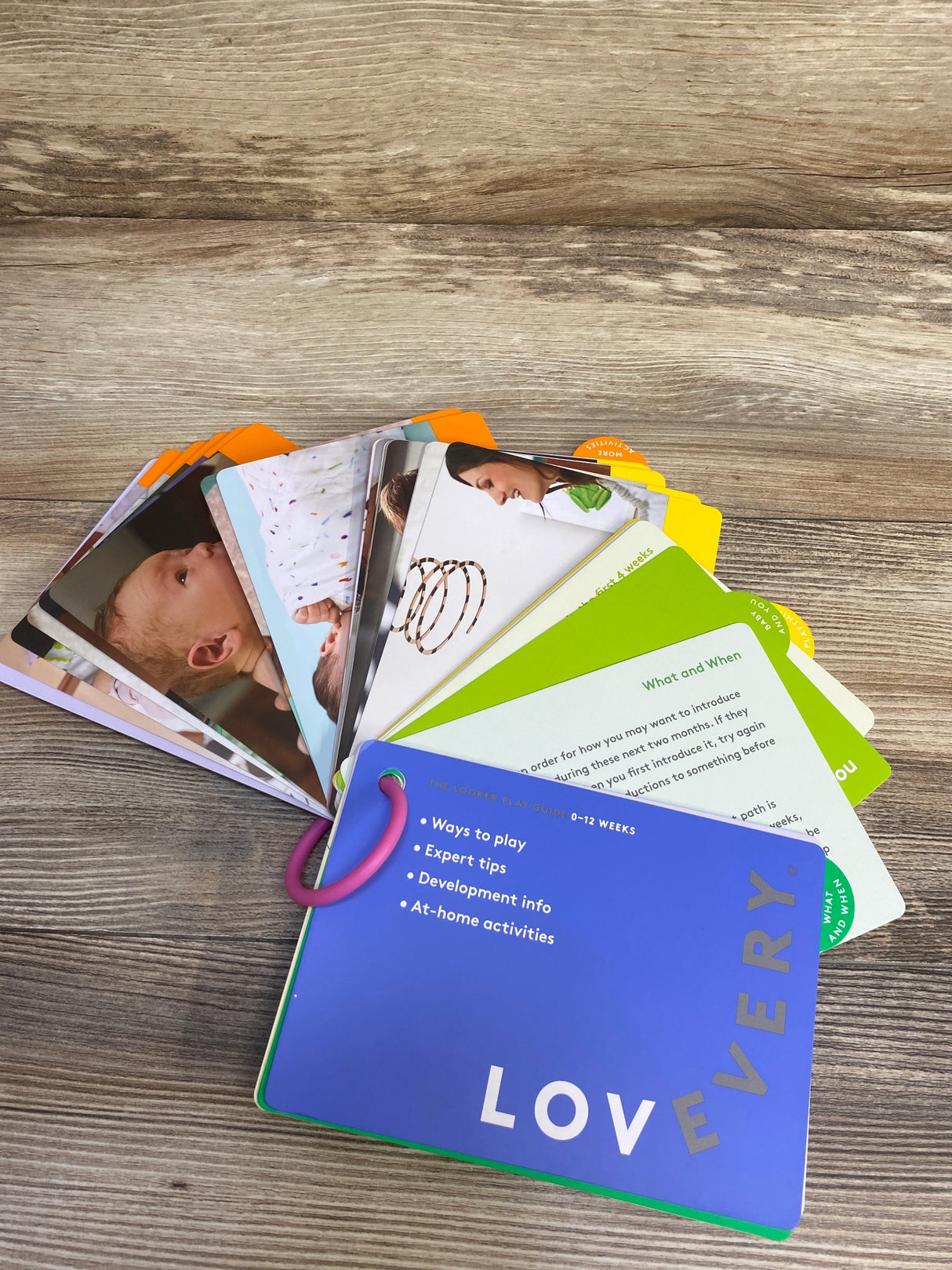 Lovevery play guide cards for babies on wood background, colorful educational activity deck