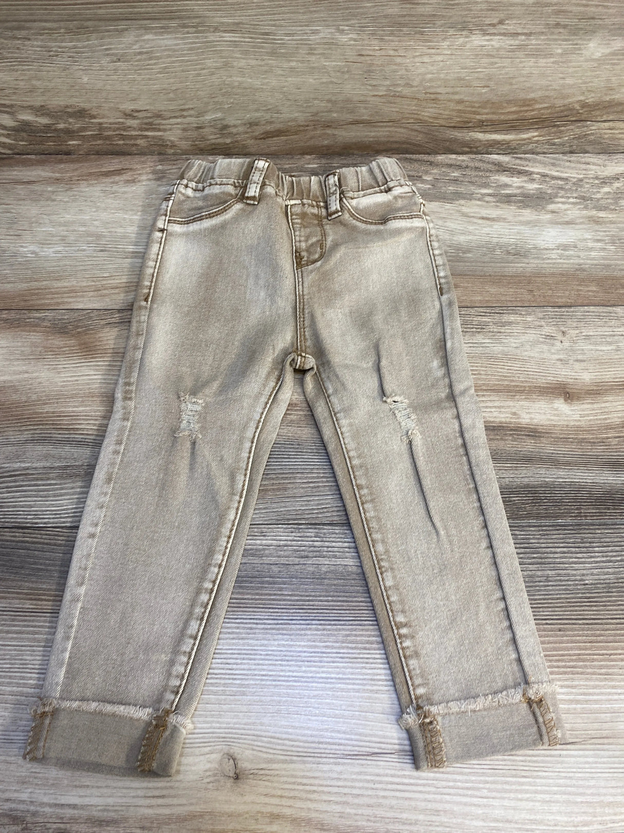 Light wash toddler jeans with elastic waistband and distressed knees on wood background