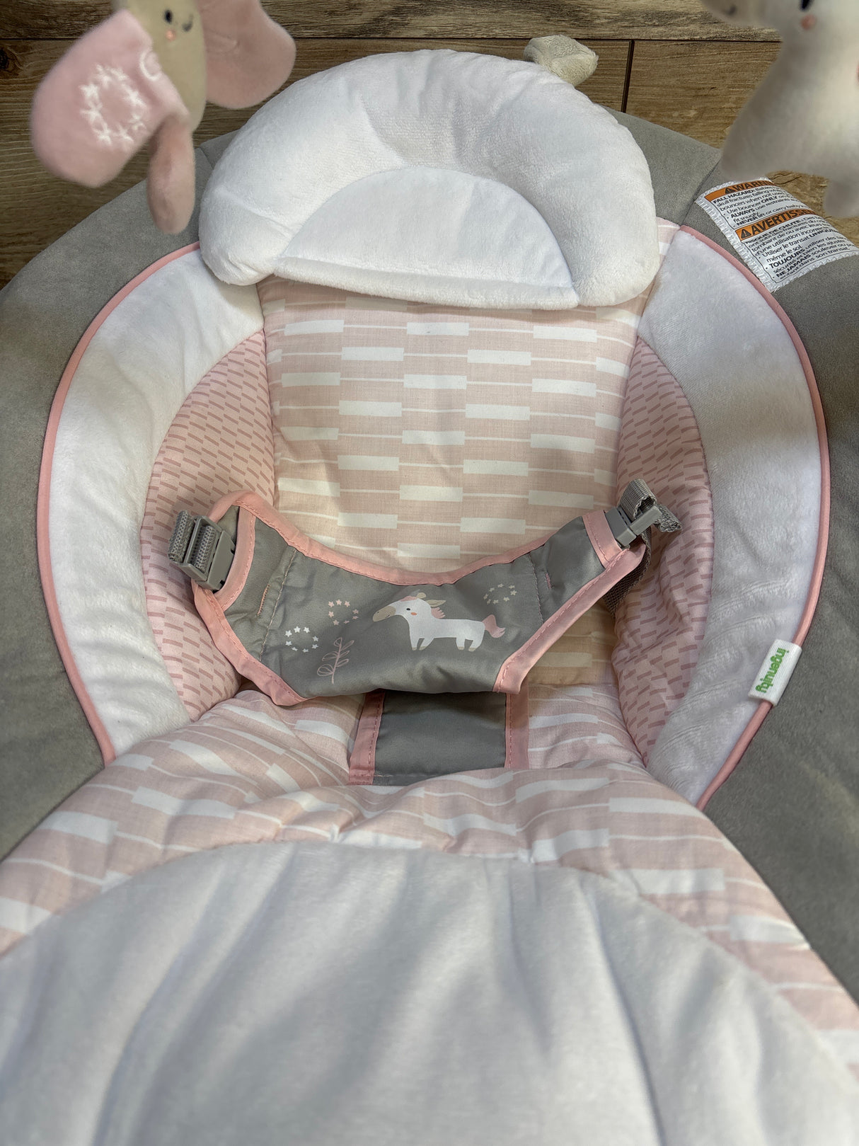Pink and gray baby bouncer with unicorn print, soft head support, and safety harness for newborns and infants.