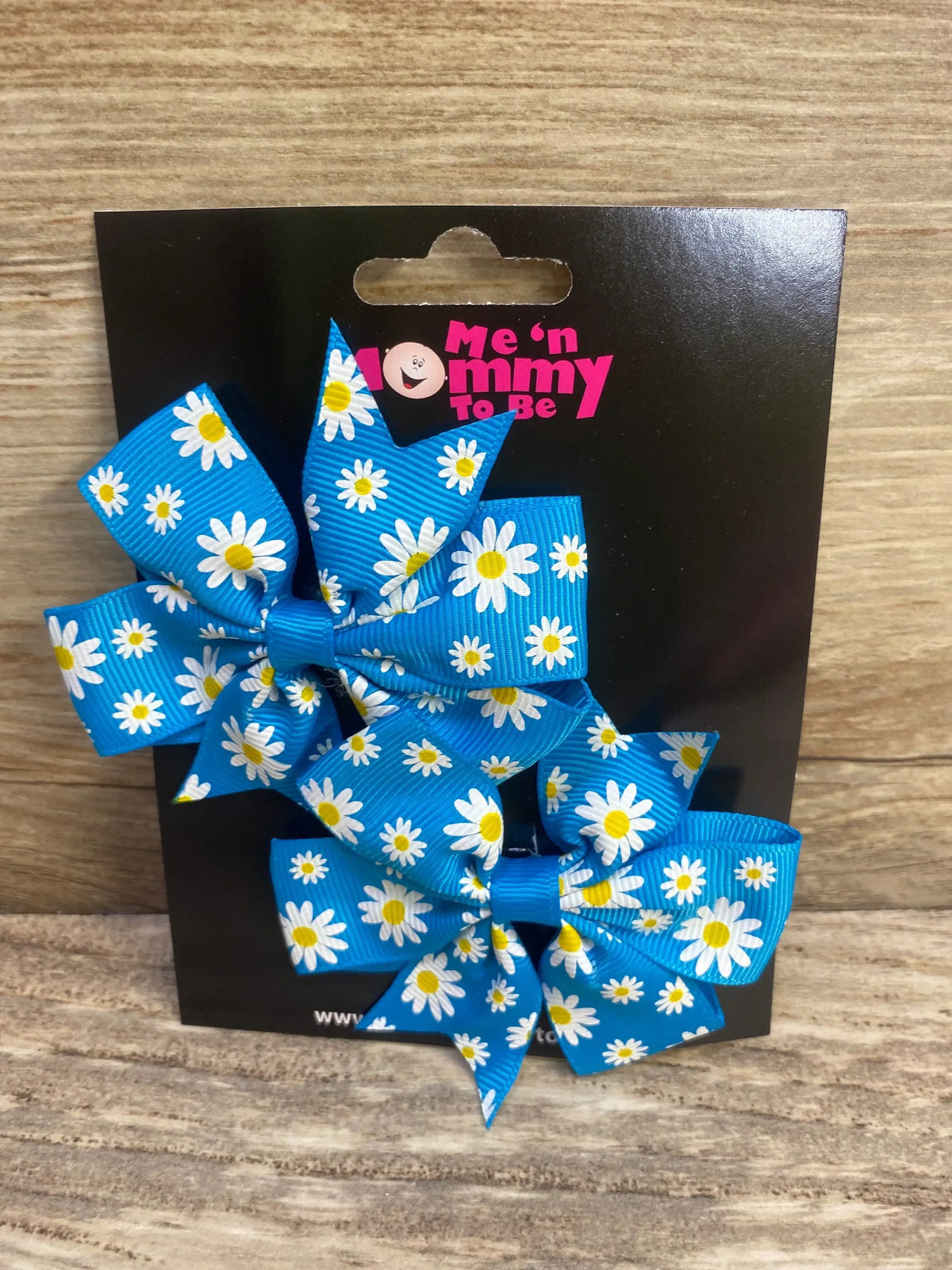 Front view of NEW Fanned Out Hair Bows Floral Blue 2pk showcasing daisy print ribbon bows on Me n Mommy To Be branded card on wood plank floor