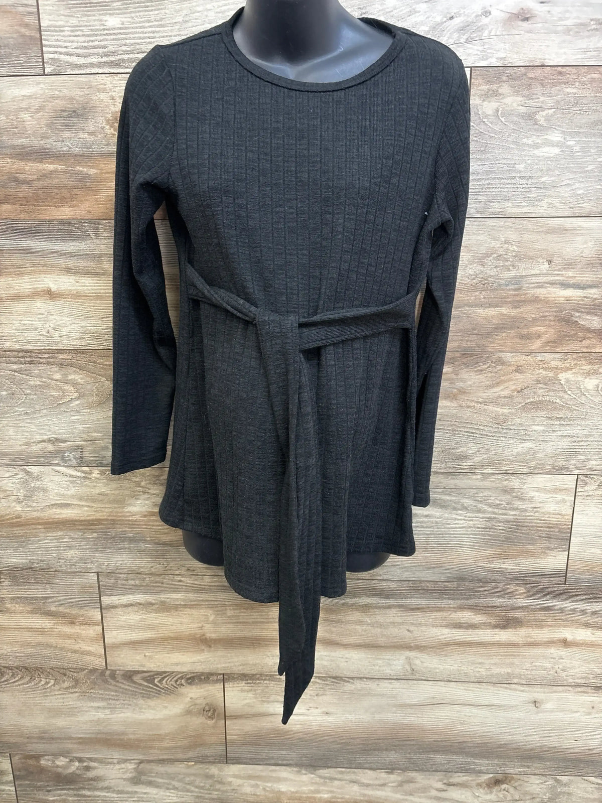 Front view of Ekouaer ribbed long-sleeve maternity top showcasing waist tie and textured fabric on wood-paneled background