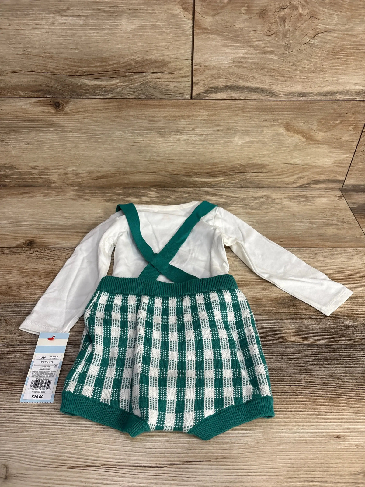 Flat-lay of 2-piece bodysuit set: white long sleeve bodysuit and green checkered knit suspender shorts with cross straps