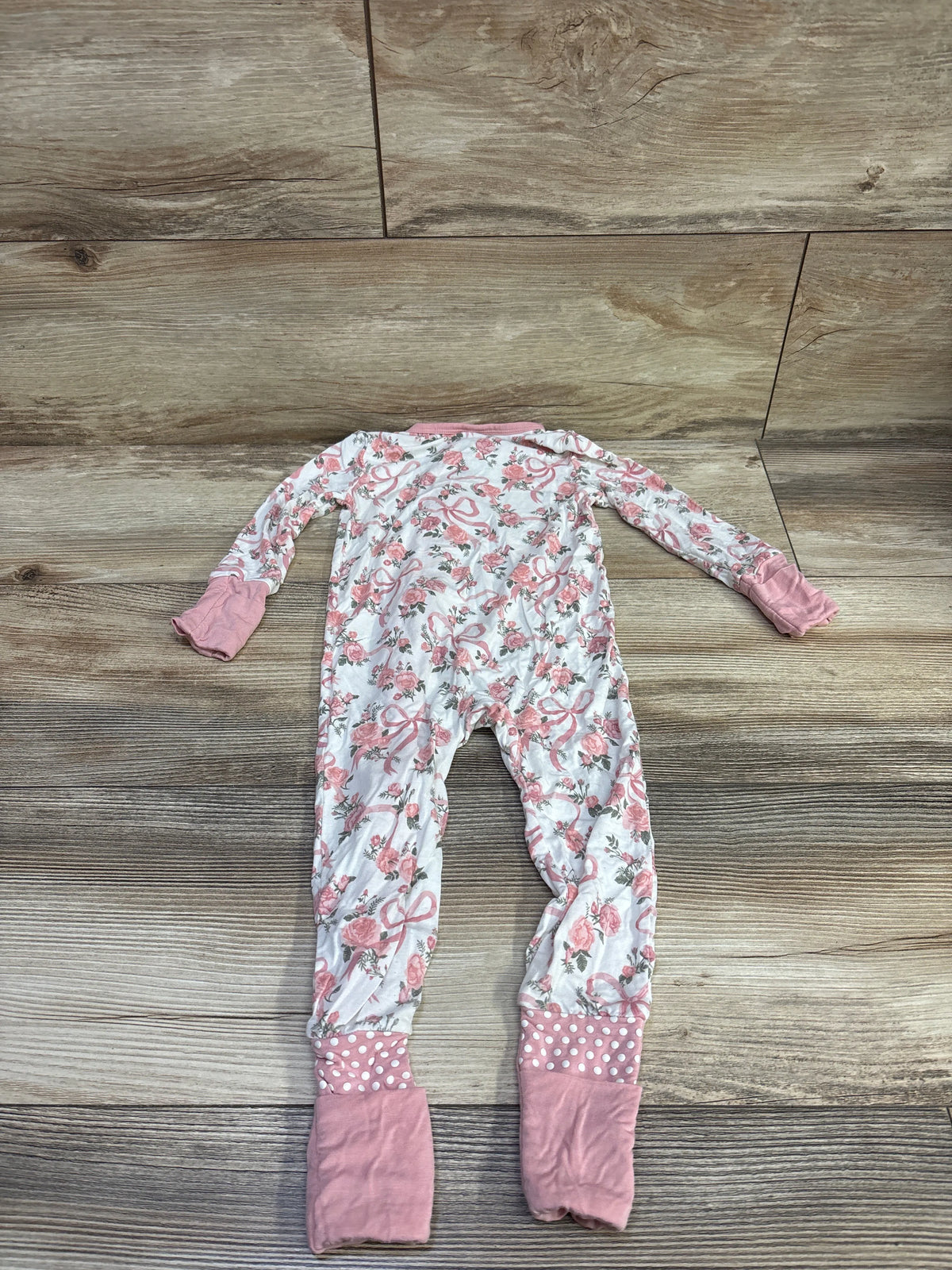 Front view of Angel Dear bamboo floral convertible zip sleeper in white with pink cuffs and foot coverings on a wood-look floor