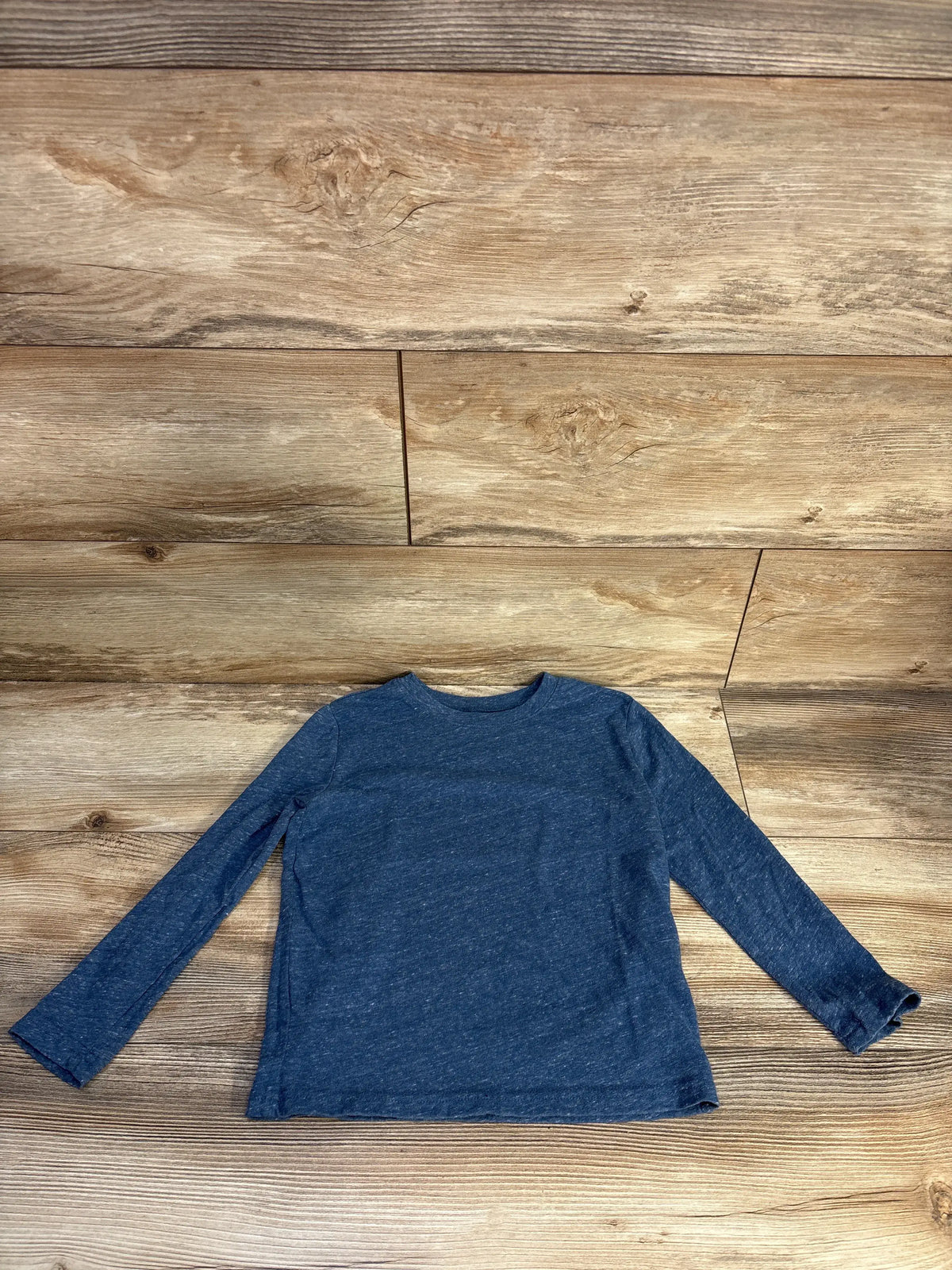 Front view of a blue Jumping Beans long sleeve shirt showcasing its relaxed fit with a wood plank background