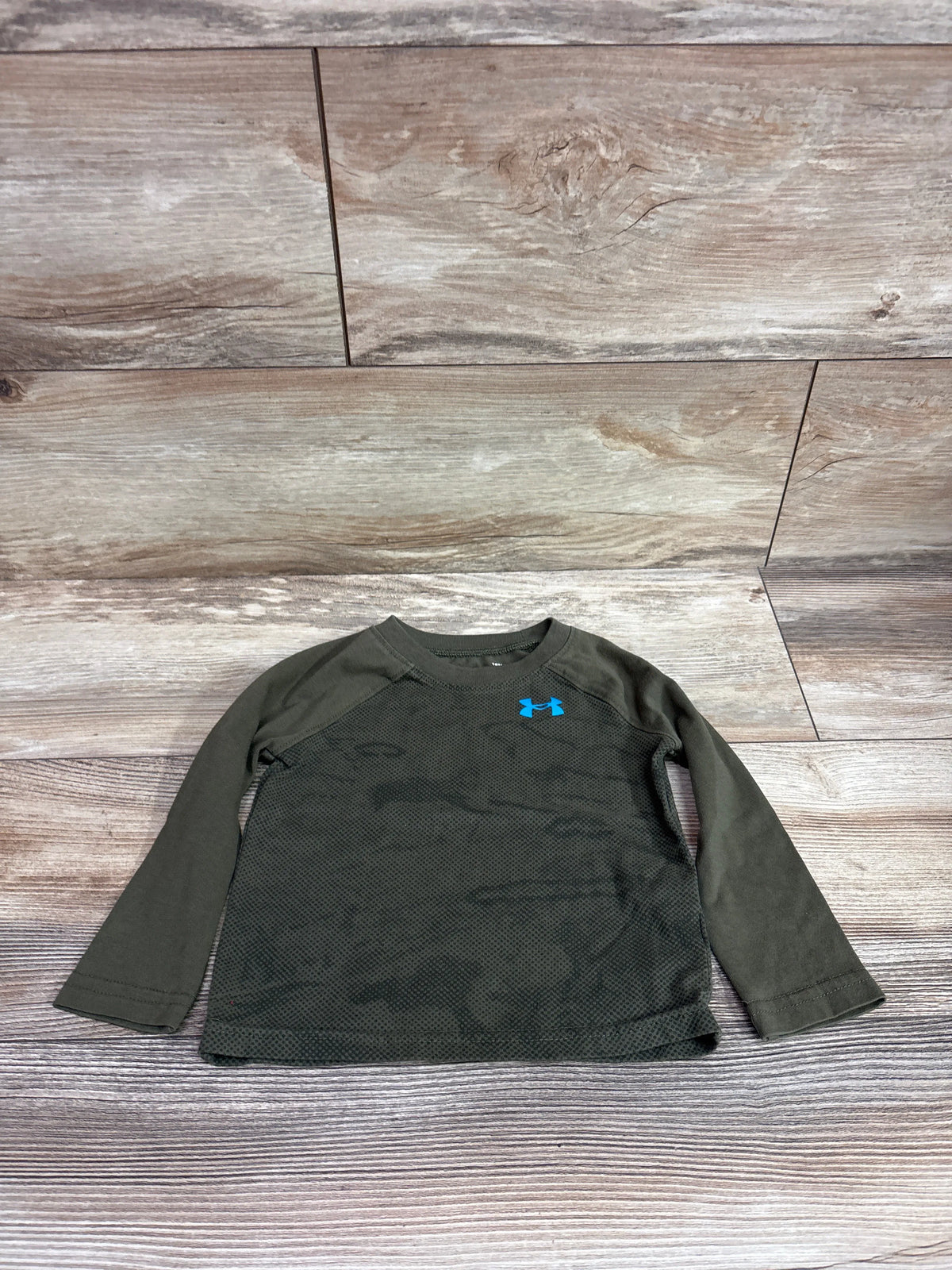 Under Armour long sleeve green baby shirt size 18m on a wood background