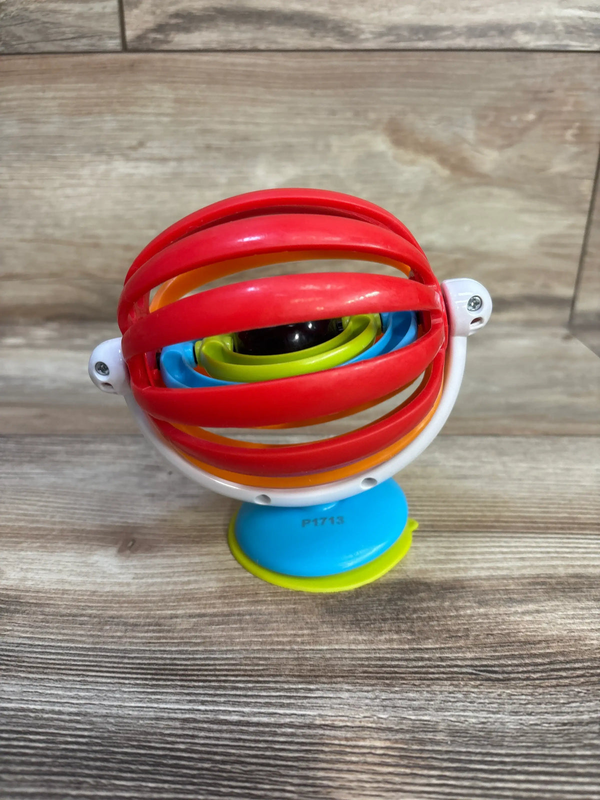 Front view of Baby Einstein Sticky Spinner High Chair Toy showcasing colorful grasp-and-spin loops and suction cup base on a wood surface