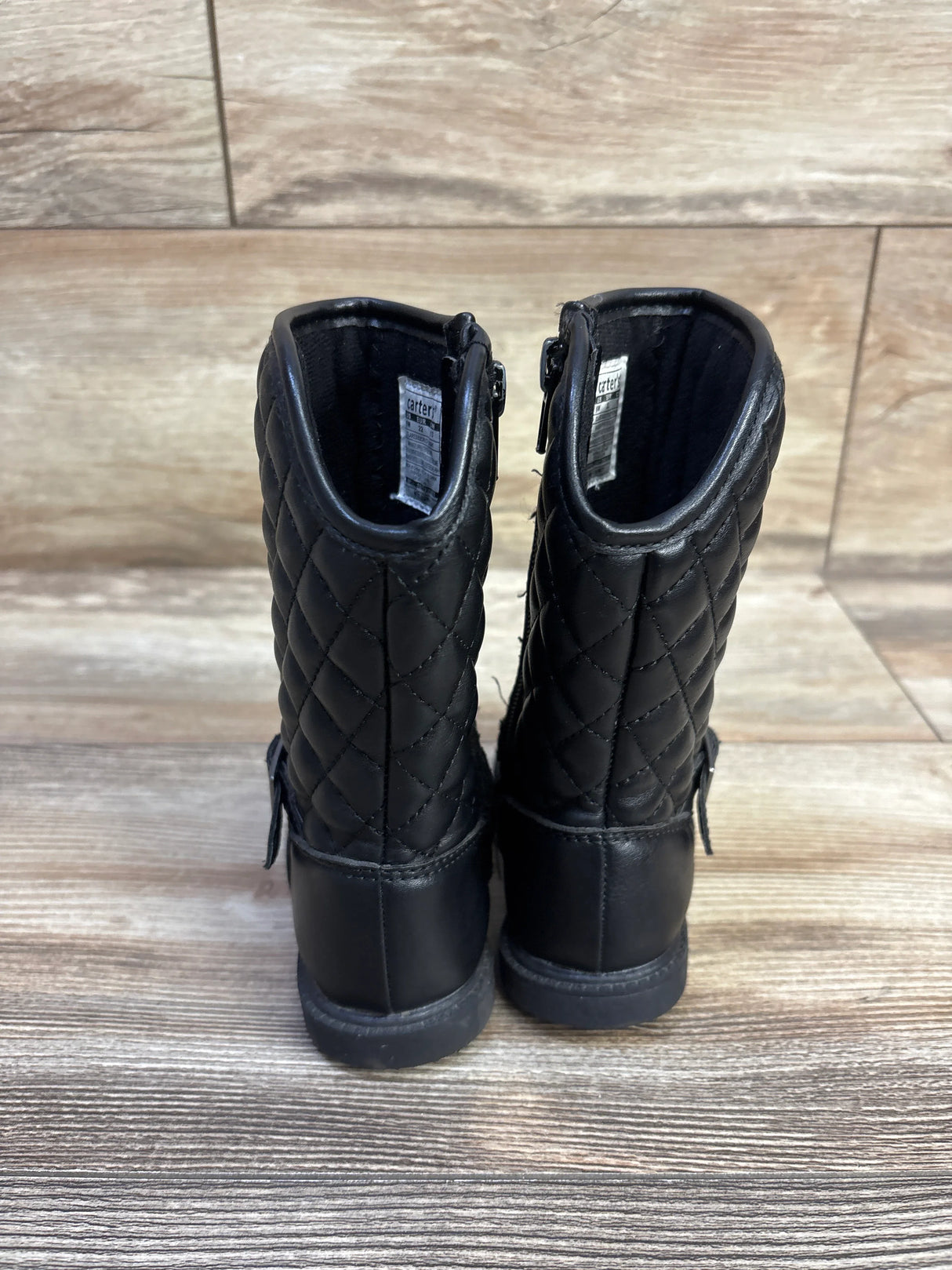 Rear view of Carter’s black quilted riding boots size 6C showing quilted shaft, back zipper and low heel on wood floor