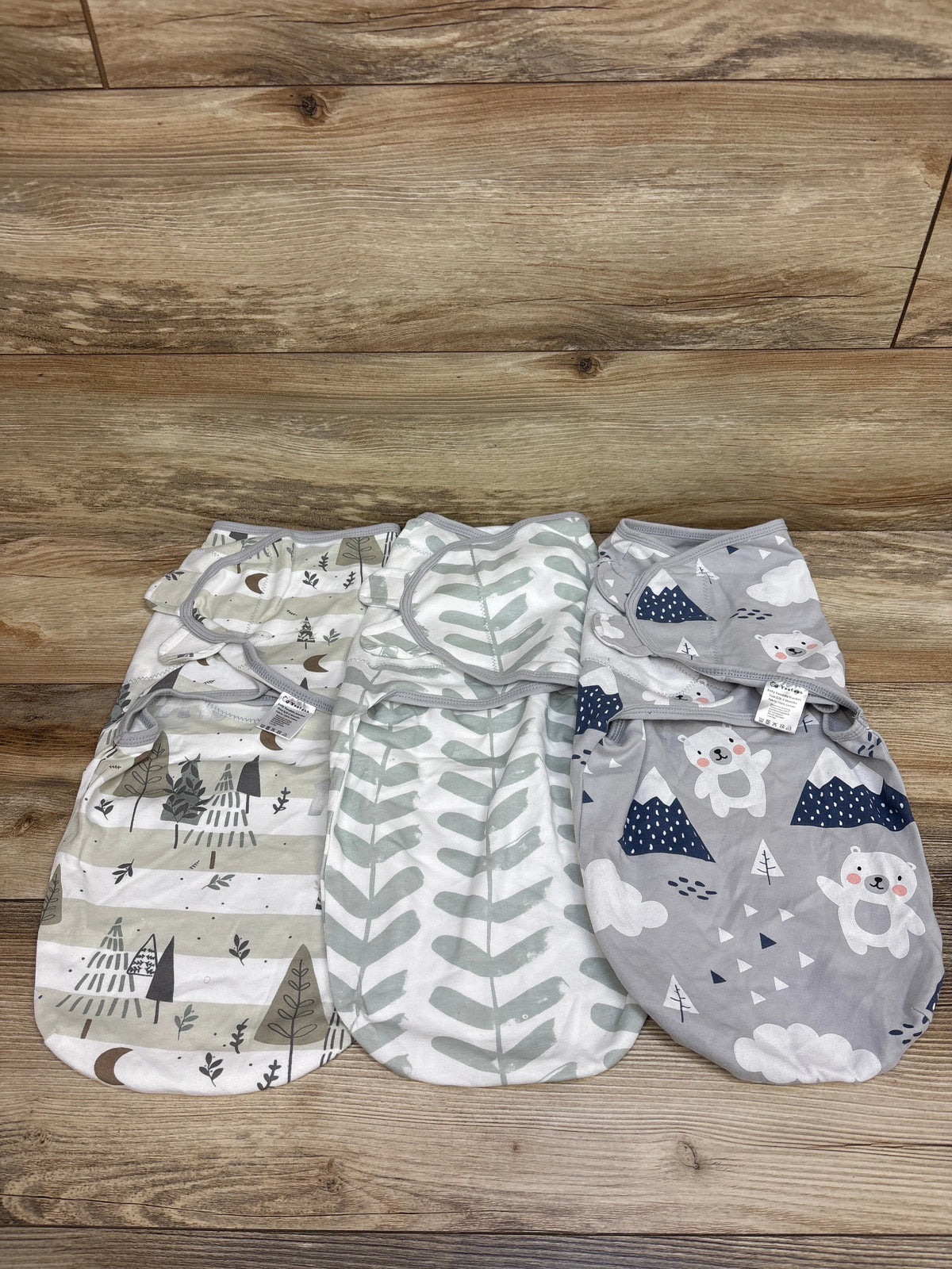 Overhead view of Yoofoss three-pack Grey swaddle wraps showcasing three patterned designs on a wood surface