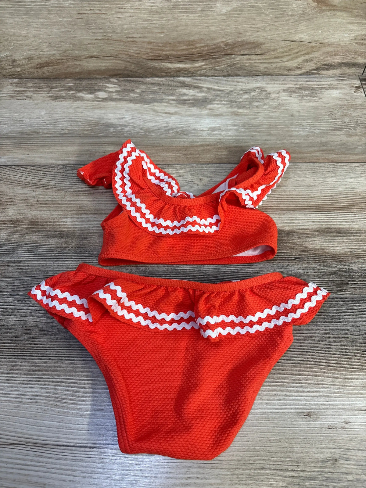 Front view of Janie & Jack two-piece orange ric-rac ruffle toddler swimsuit showing ruffle and ric-rac trim on white background