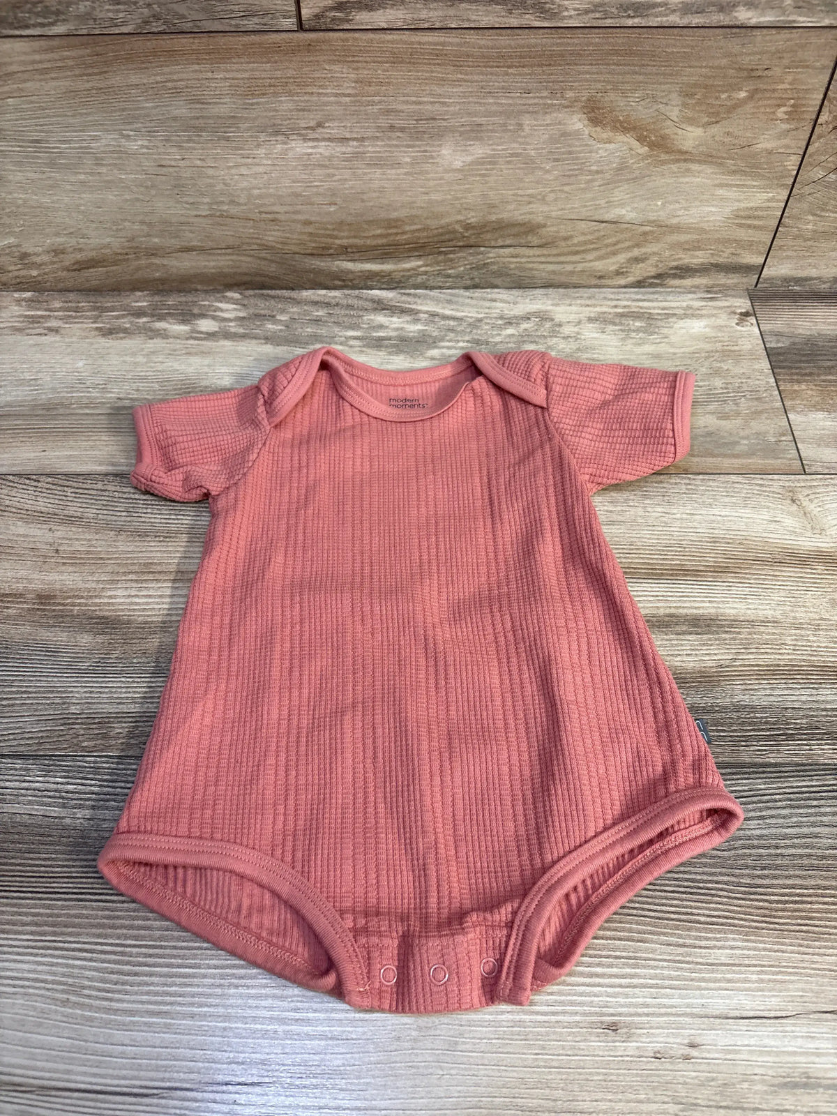 Front view of a red Modern Moments waffle knit bubble romper with short sleeves and snap closures on a wood floor