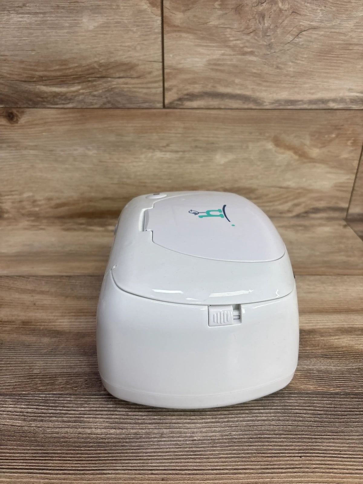 Front view of Hiccapop Ultra Wipe Warmer in white showcasing front slider latch and top lid with a wood tabletop background