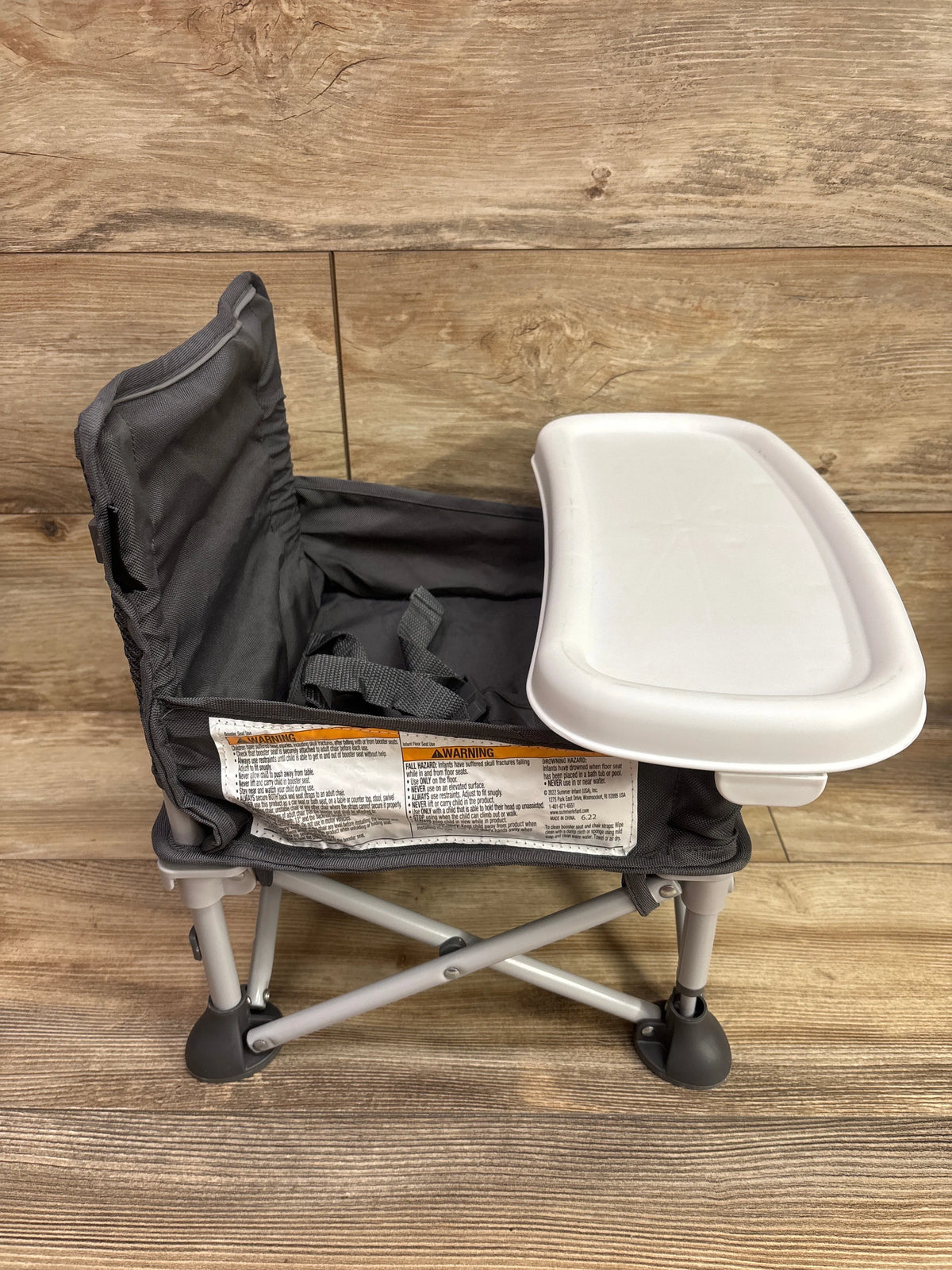 Grey Summer Infant Pop 'N Sit Portable Infant Booster Seat with white tray on wood floor