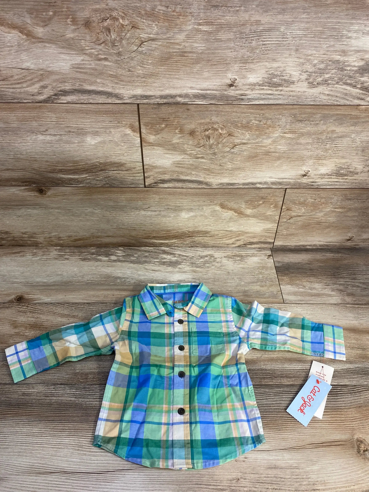 Children's long-sleeve plaid shirt in green, blue, yellow, and white on wooden floor