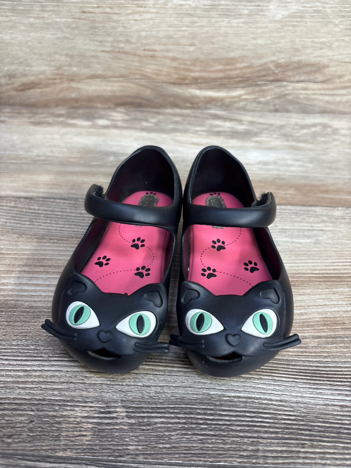 Black kids shoes with green-eyed cat face design and pink insoles with black paw prints